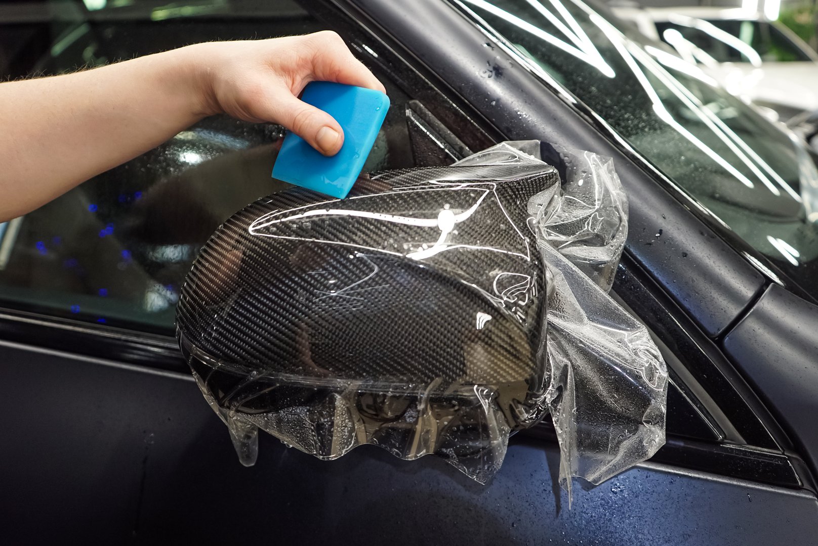 The process of installing PPF on the side mirror. Car wrapping close-up. Car wrapping. A car wrapping specialist applies a polyurethane film to the car. Selective focus. PPF protective film.