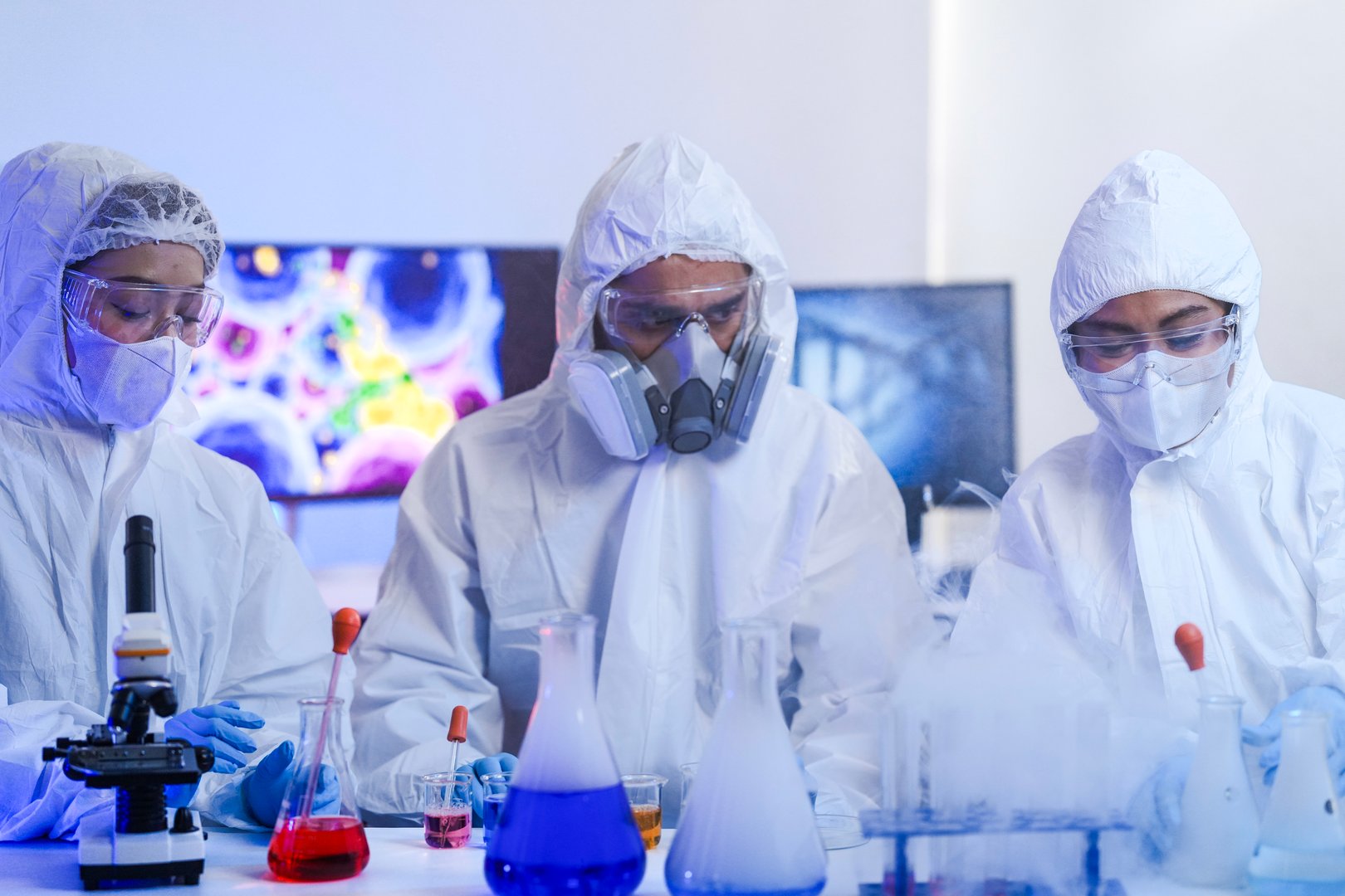 A team of scientists in hazmat suits works on a vaccine in a high-security biocontainment lab. Concept for pandemic response, virology, and medical research.