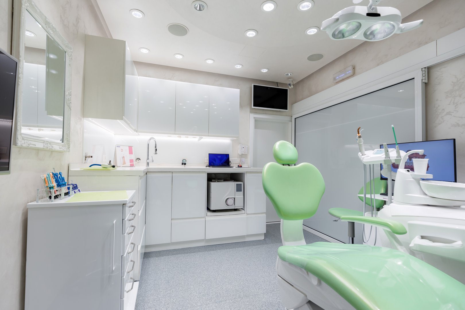 A sleek dental office features a green chair, bright lights, and modern amenities for patient care.