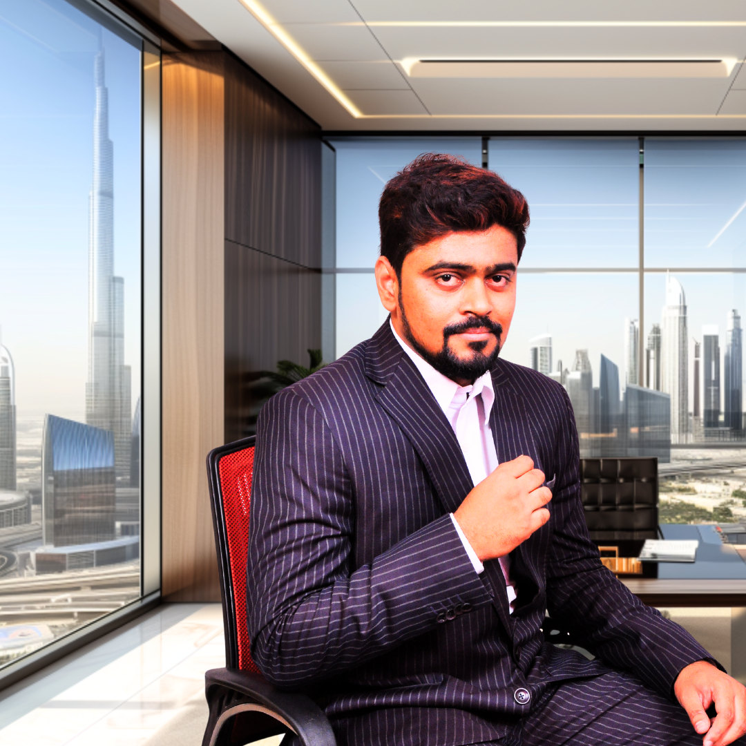 Man in a striped suit sitting in a modern office with a city skyline, including a tall skyscraper, visible through large windows.