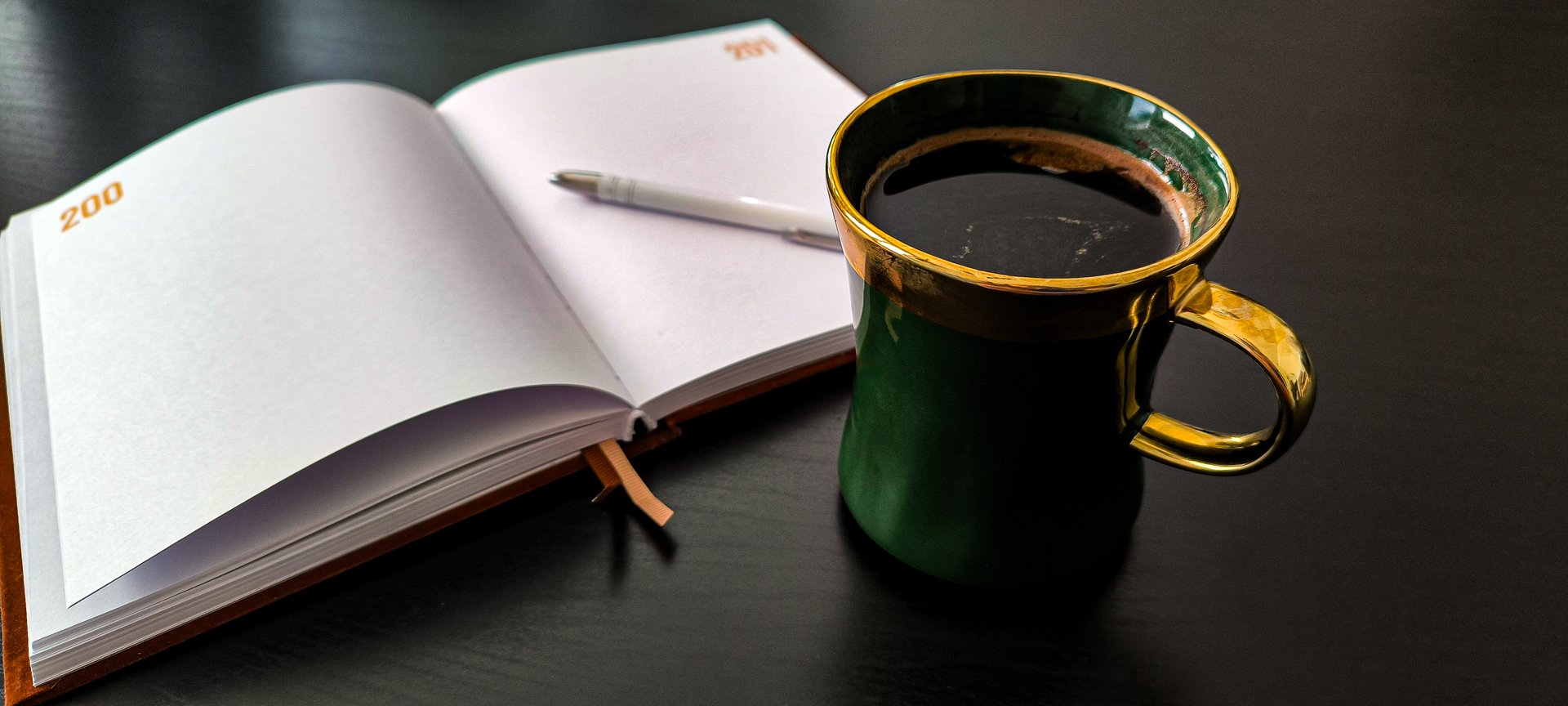 An elegant cup of hot, freshly brewed coffee with a notepad. Morning routine. Planning the day. Enjoy a calm morning. Morning relaxation. Notebook for writing and planning.