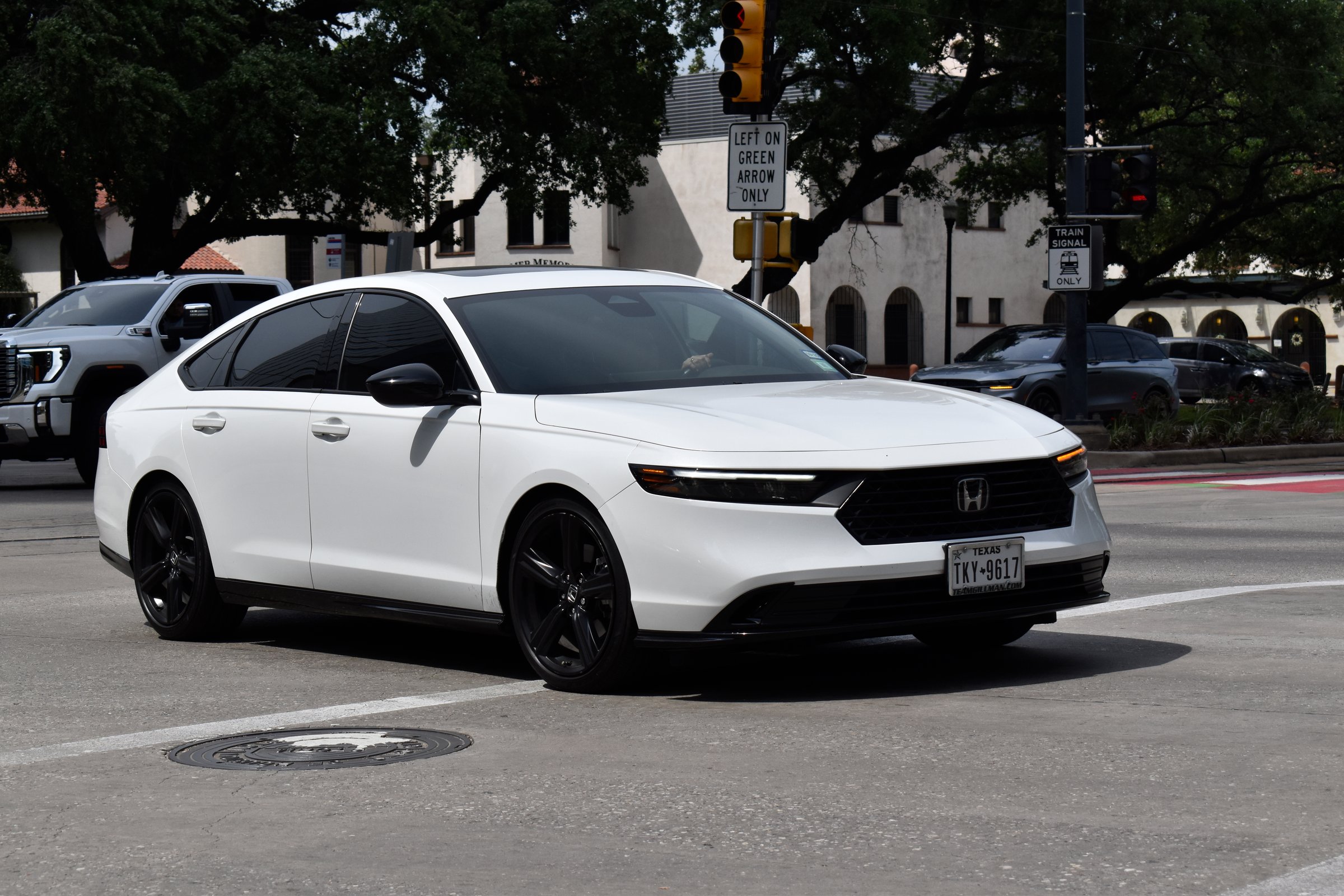 Houston, TX USA - 4/18/2024 - A portrait of a white Honda Accord sedan cruising in a downtown district near Hermann Park.