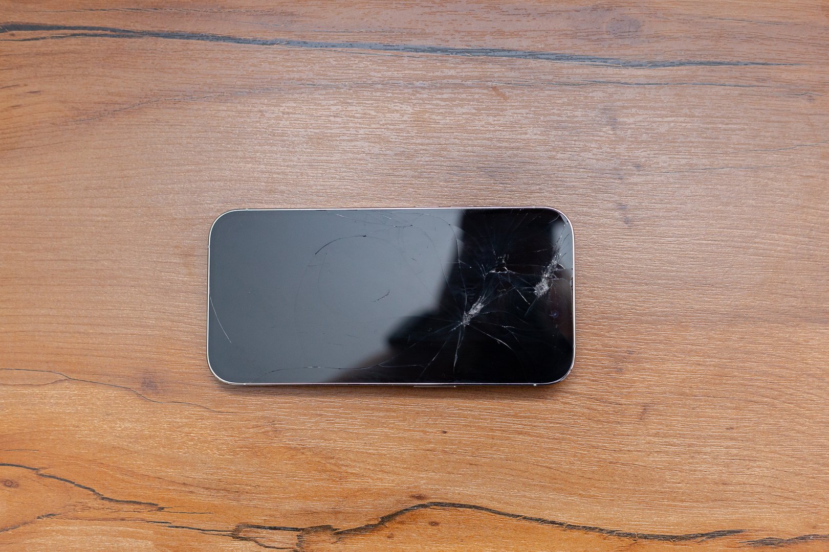 Cracked Smartphone Placed On Wooden Table For Documentation