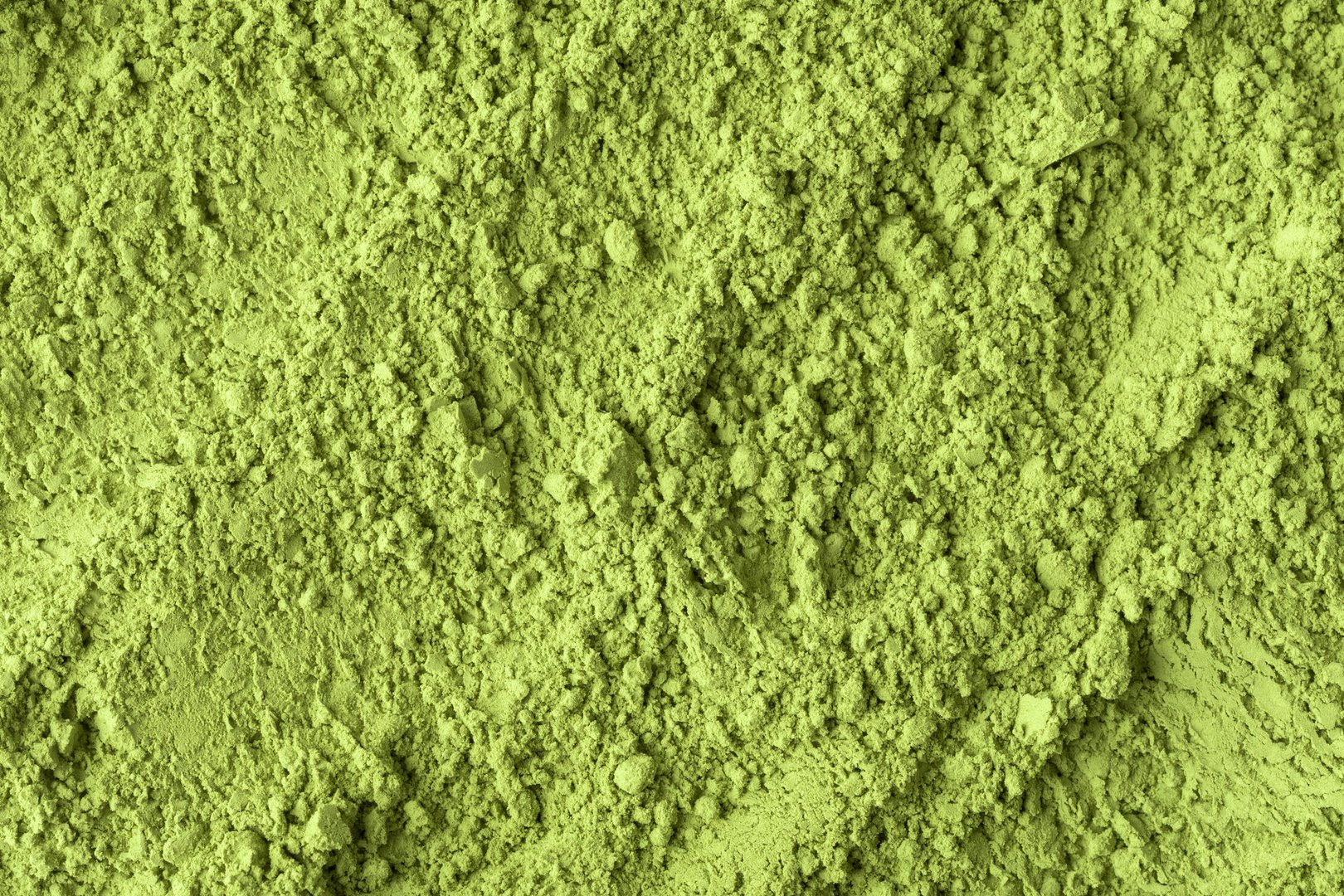 Detailed close-up of vibrant green matcha powder reveals rough uneven texture and organic surface perfect for food backgrounds.
