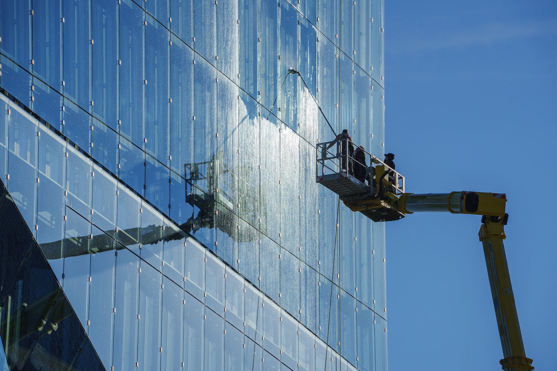 Berlin, Germany, 6/2/2024, Maintenance works being done on a building. Workers are cleaning windows from a boom lift