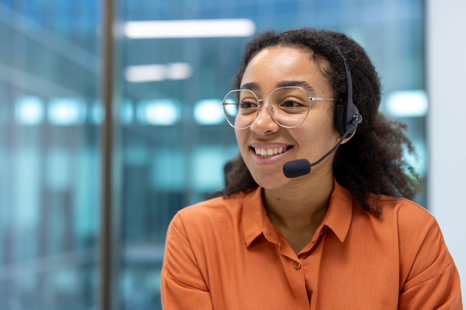 Confident customer support agent wearing headset smiling in modern office. Professional atmosphere conveys communication, service, and success in workplace. Ideal concept for call centers.