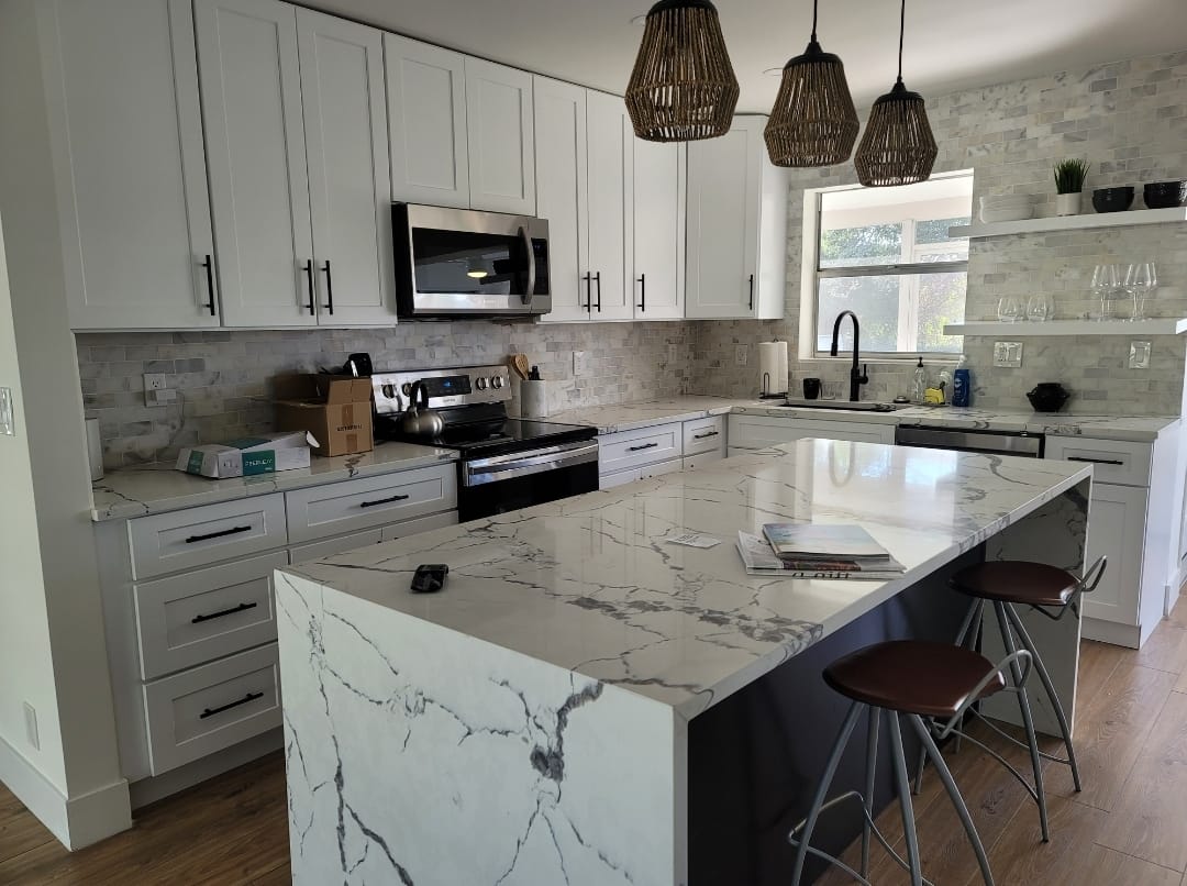 Kitchen interior with bar stools white countertops wooden cabinets pendant lighting extra kitchen sink glass cabinets hardwood floors stainless steel appliances window with coverings blinds drawn