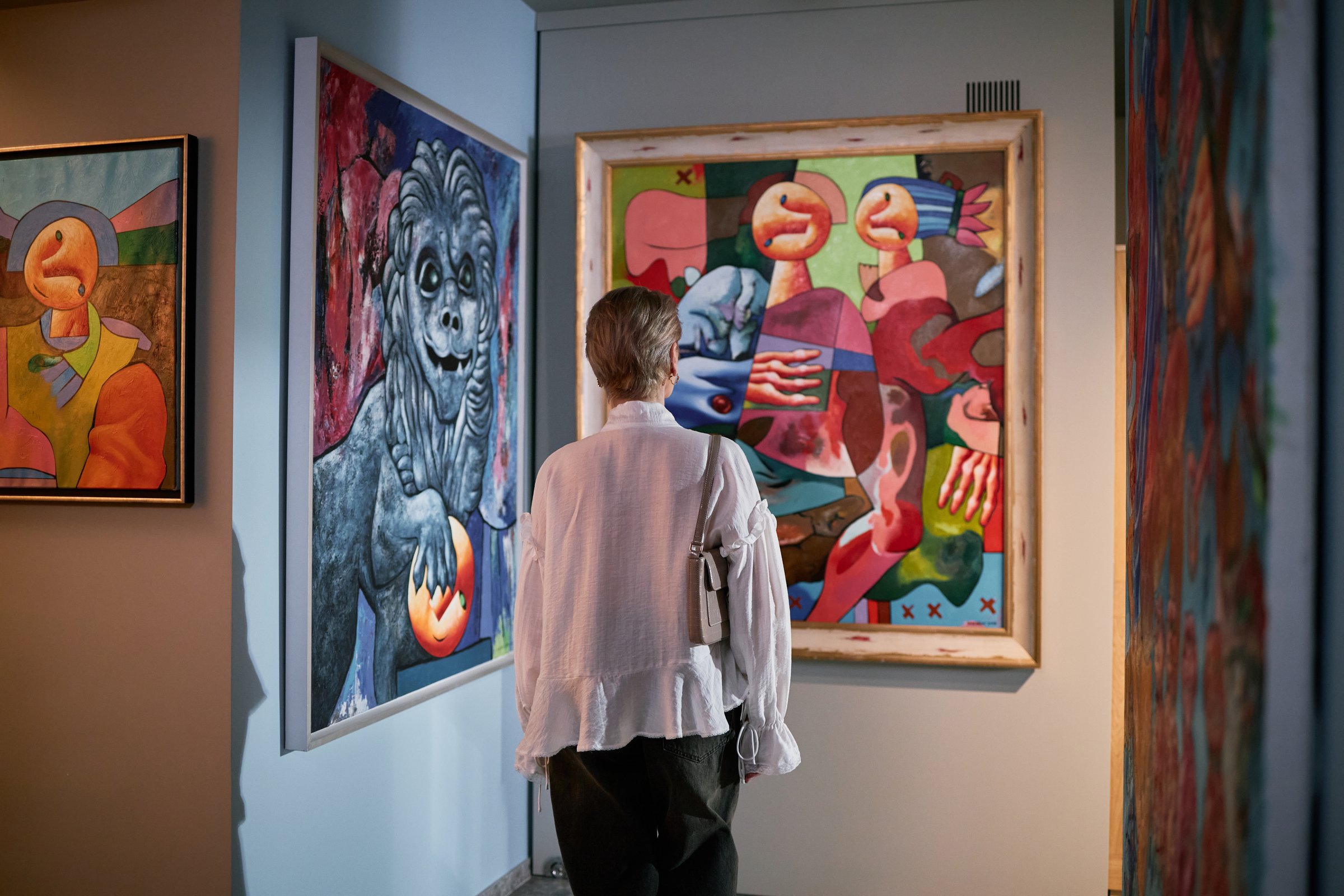 Senior individual admiring vibrant paintings in an art gallery exhibiting modern artistic expressions and abstract elements