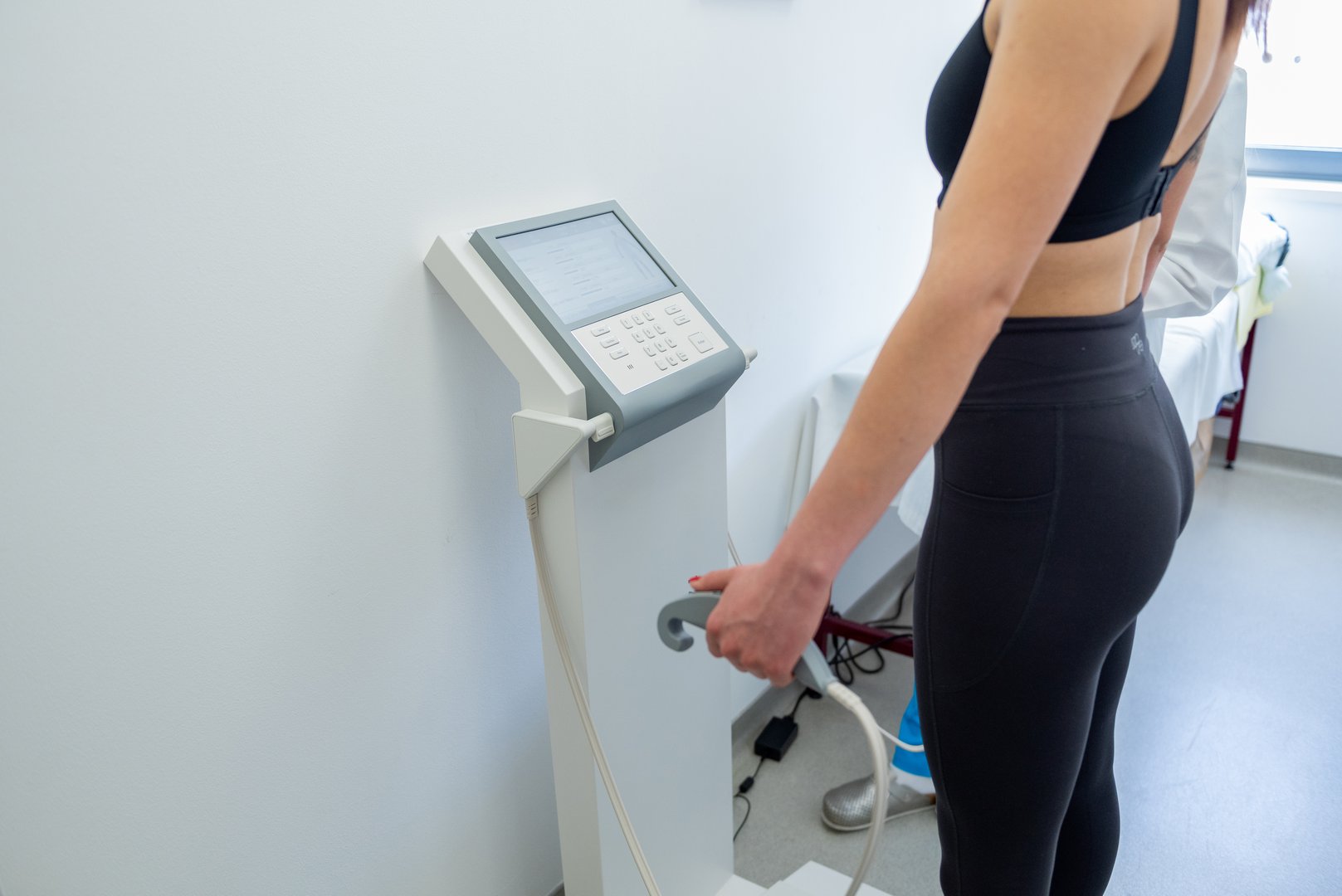 A health practitioner assists a woman with a body composition test using advanced equipment.