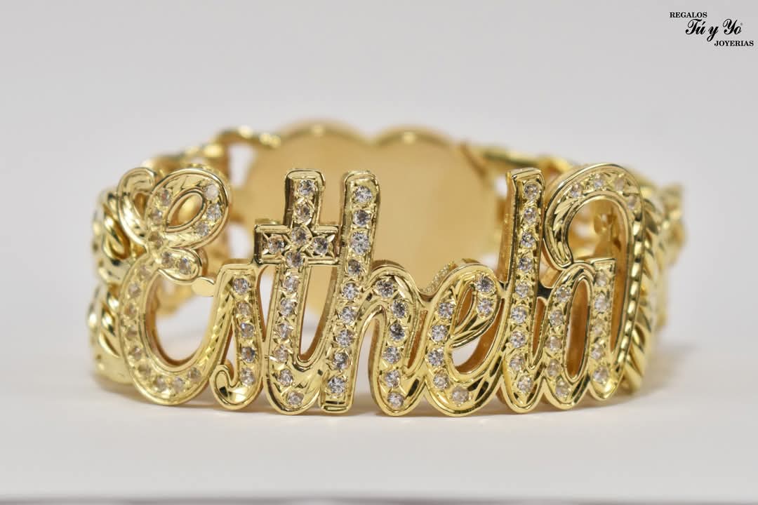 Gold bracelet with cursive "Esthela" inlaid with small diamonds, featuring a decorative design on the band.