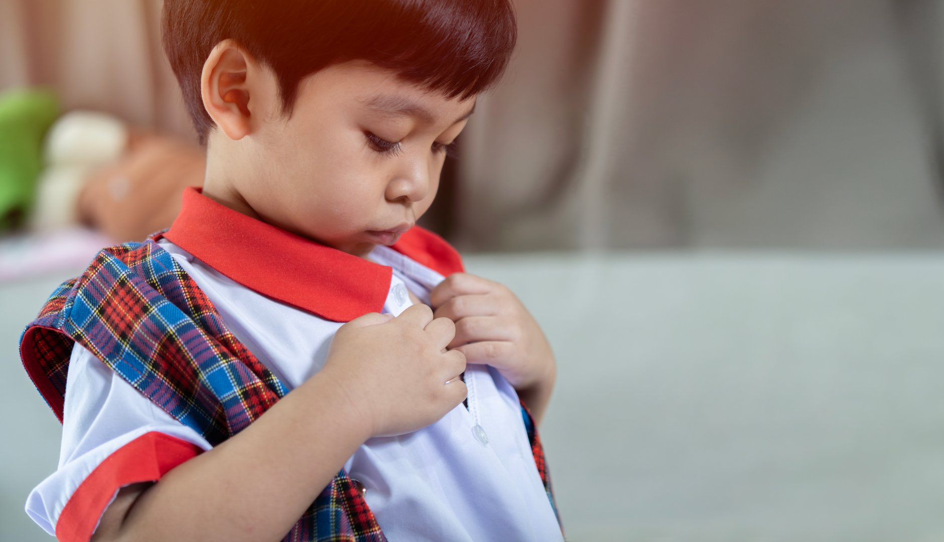 Close up of an Asian little boy learning get dressed, buttoned white shirt and get ready for school, Early Education concept.
