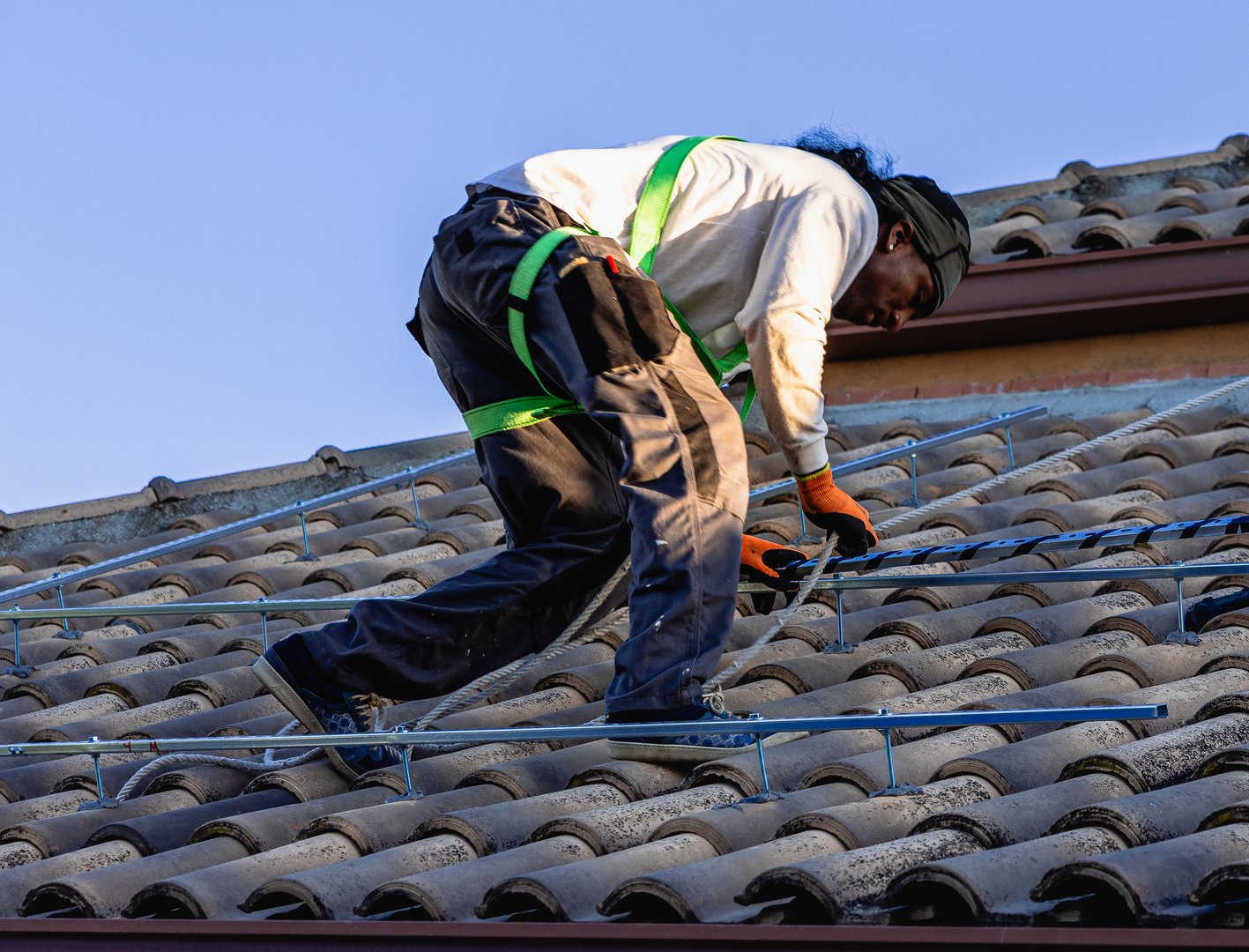 Man installing photovoltaic system rails on a house roof