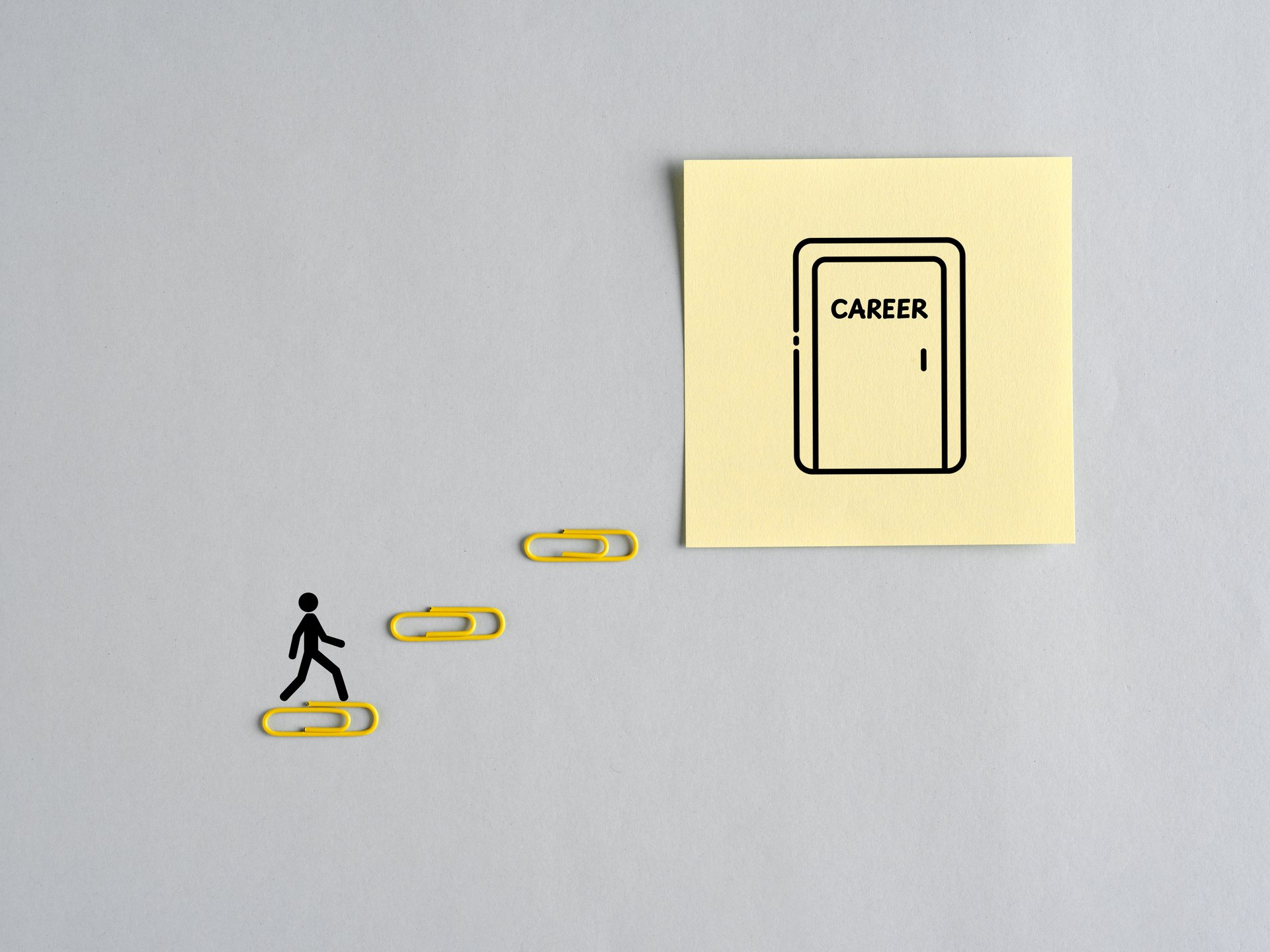 Career development and growth concept with businessman using paper clips as stairs to reach professional career goals.