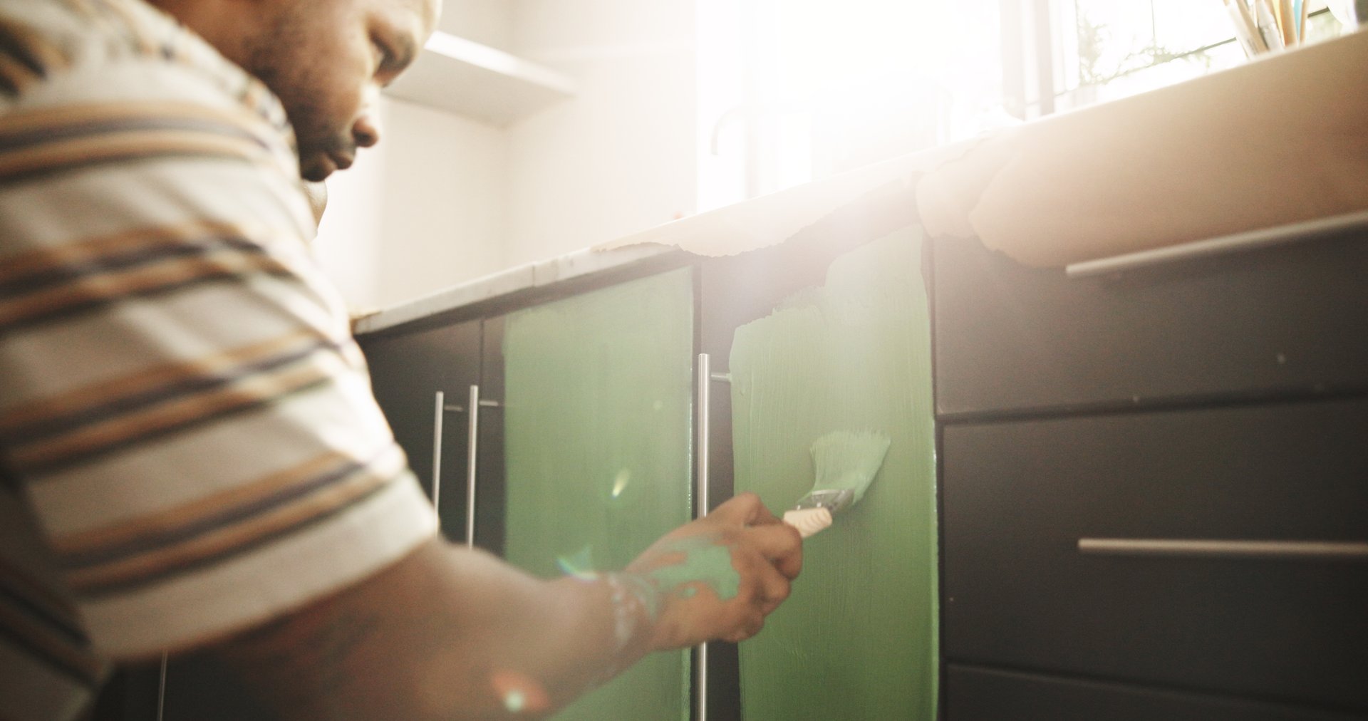 Painting, remodeling and black man in kitchen for diy project, renovation and creative decoration. Interior design, cupboard and person with color for home improvement, upgrade and maintenance