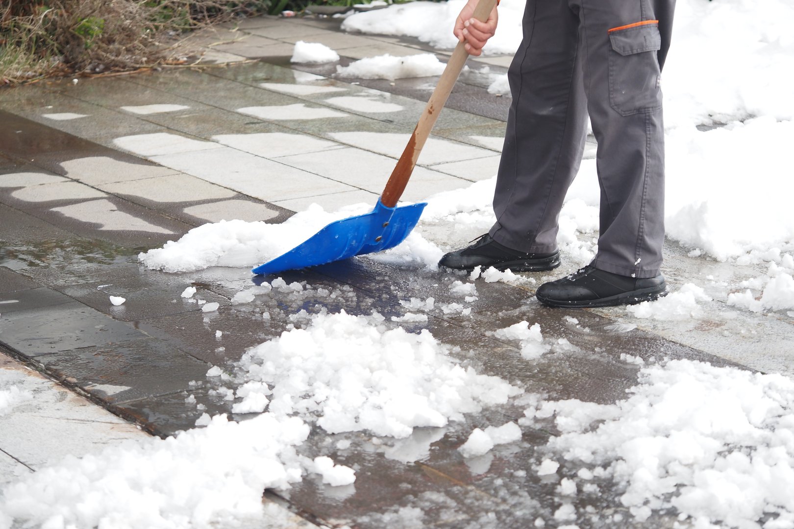 Person clears snow from a walkway on a chilly winter day.