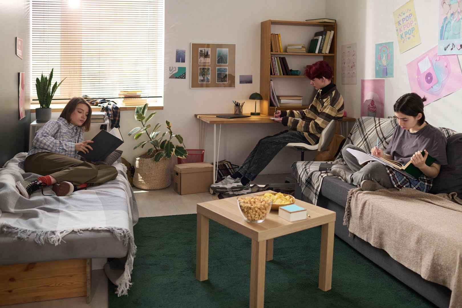 College dorm scene with three teenage friends studying in dorm room with separate activities