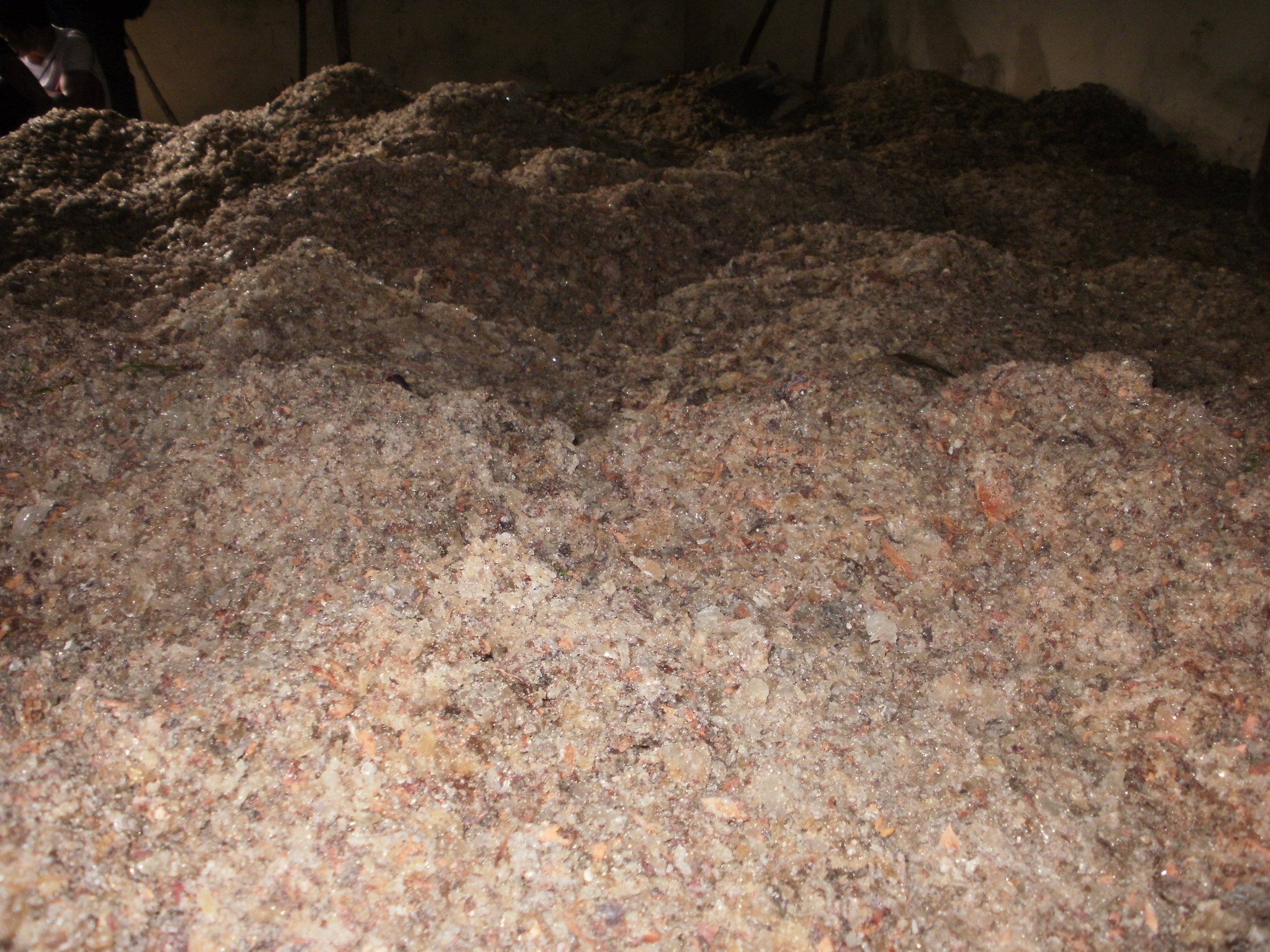 A textured background of pink and tan loose-fill cellulose insulation, commonly used for home energy efficiency.