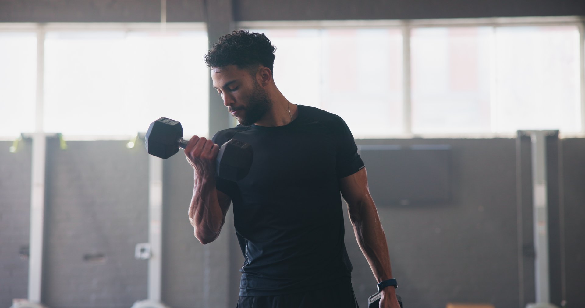 Dumbbells, fitness and man in gym, training and energy with exercise, strength and challenge. Healthy person, athlete and bodybuilder in wellness center, resilience and workout with power or progress
