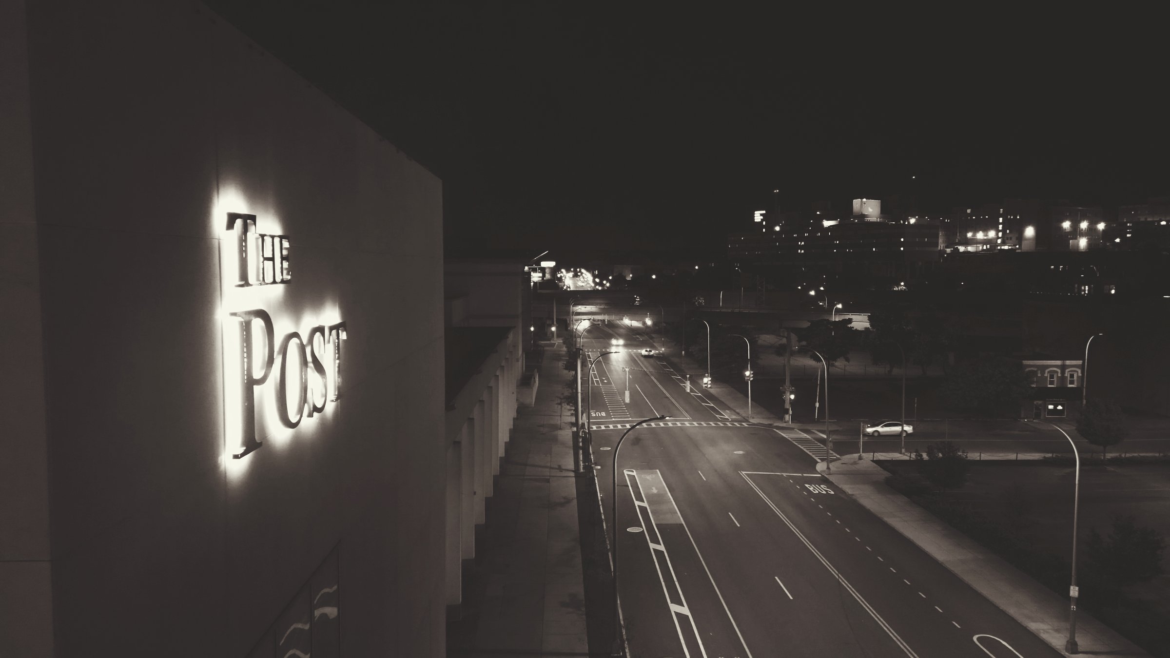 Syracuse, NY, USA - December 8, 2024. A slow and cinematic shifting of settings starting from the illuminated name of a local legacy of media and expanding into the urban corridor of a city street and the attributes of a metro that accompany it