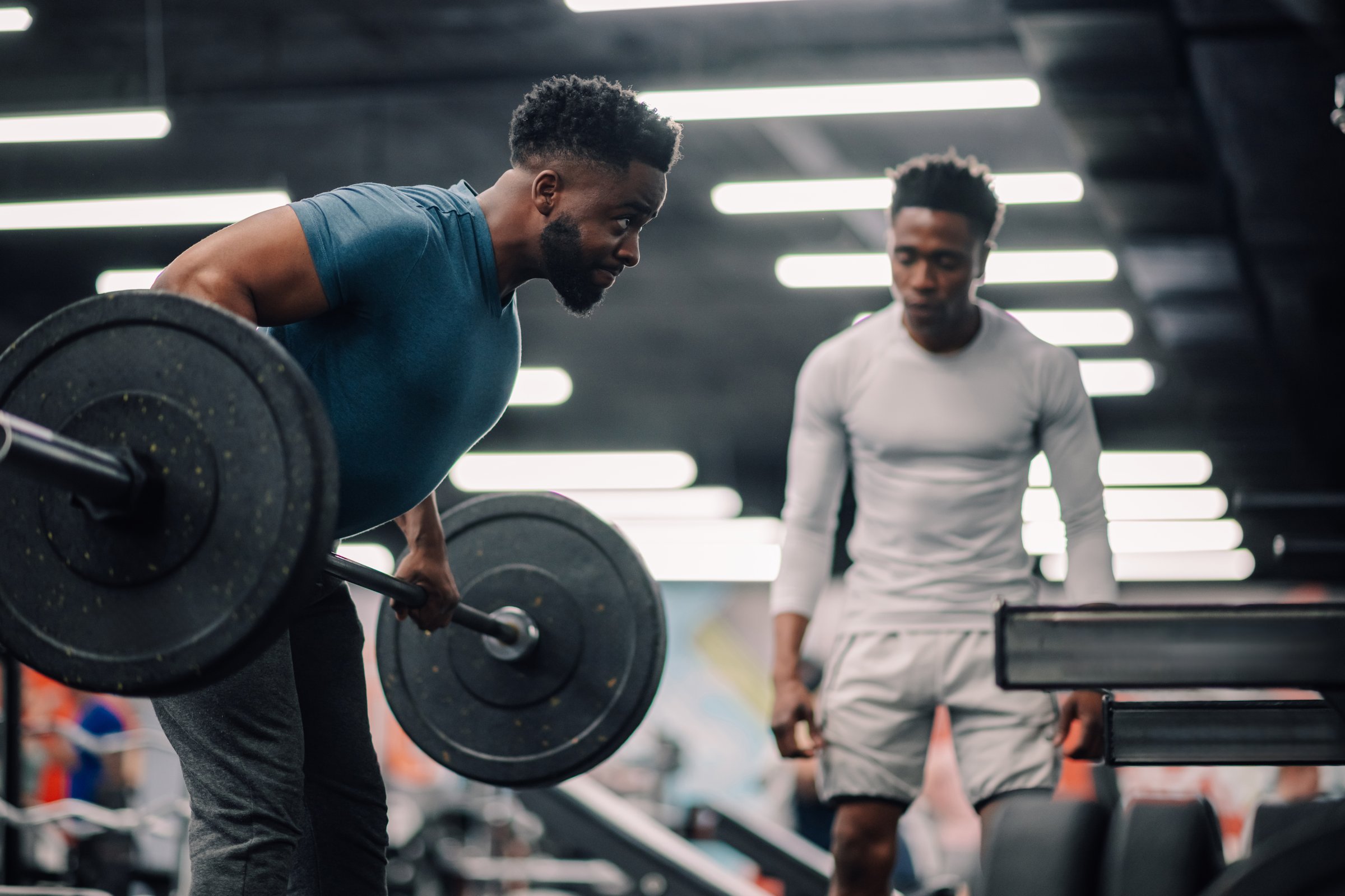 Young man focused on lifting a barbell with weights in the gym