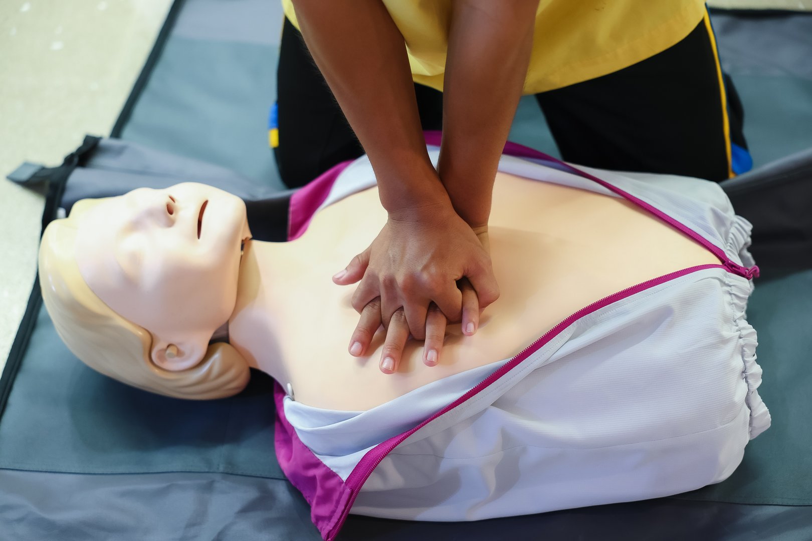 A person performs CPR chest compressions on a during a training session, highlighting essential life-saving techniques and emergency preparedness.
