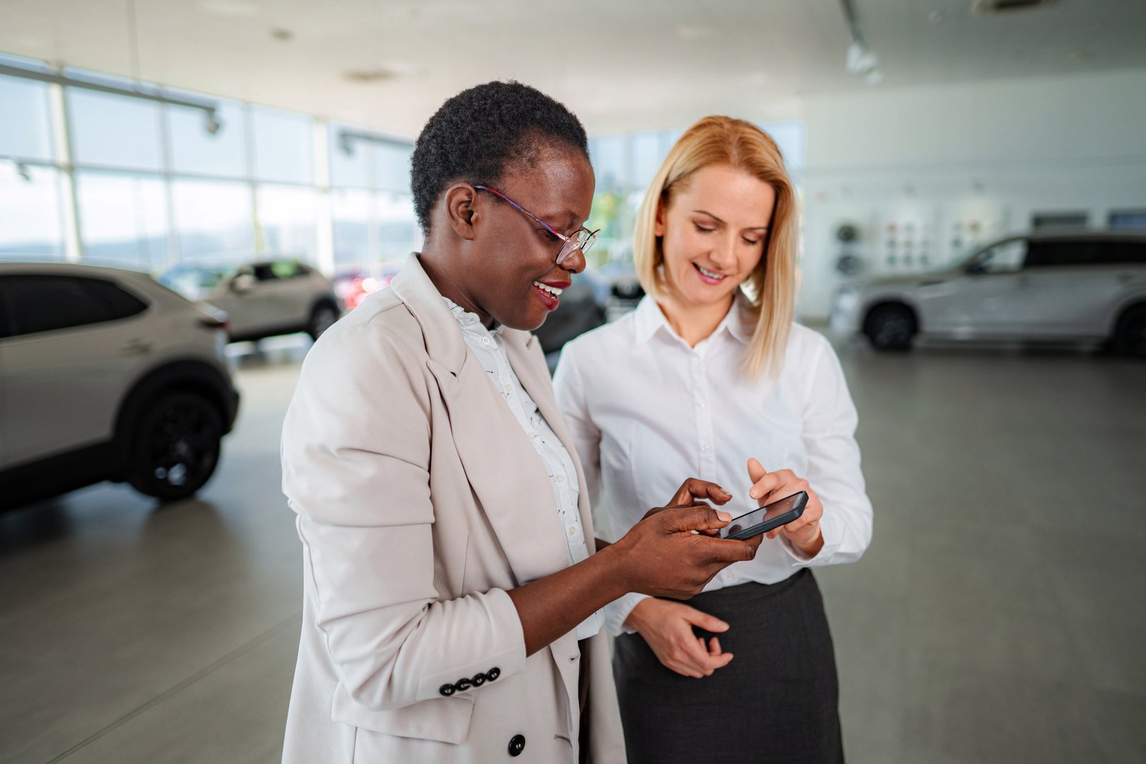 Car salesperson helping customer making purchase decision with smartphone