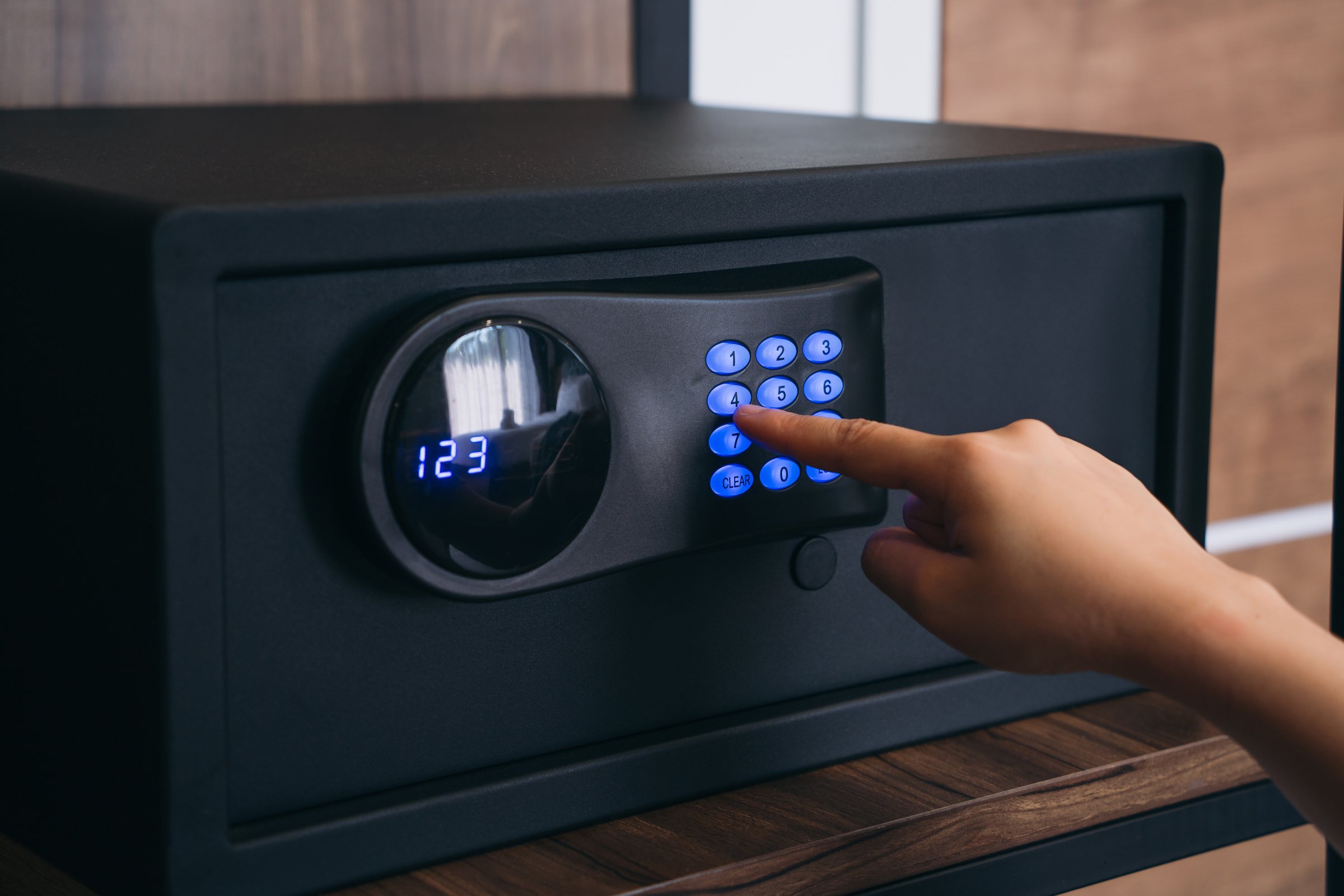 Close-up of a person hand entering a password to unlock and open the safe box door.
