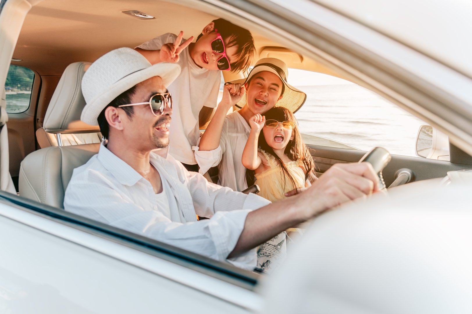 Portrait of  family enjoying beach trip with their favorite car. Parents and children are traveling the way to the sea.Holiday and travel family concept, Summer vacations.