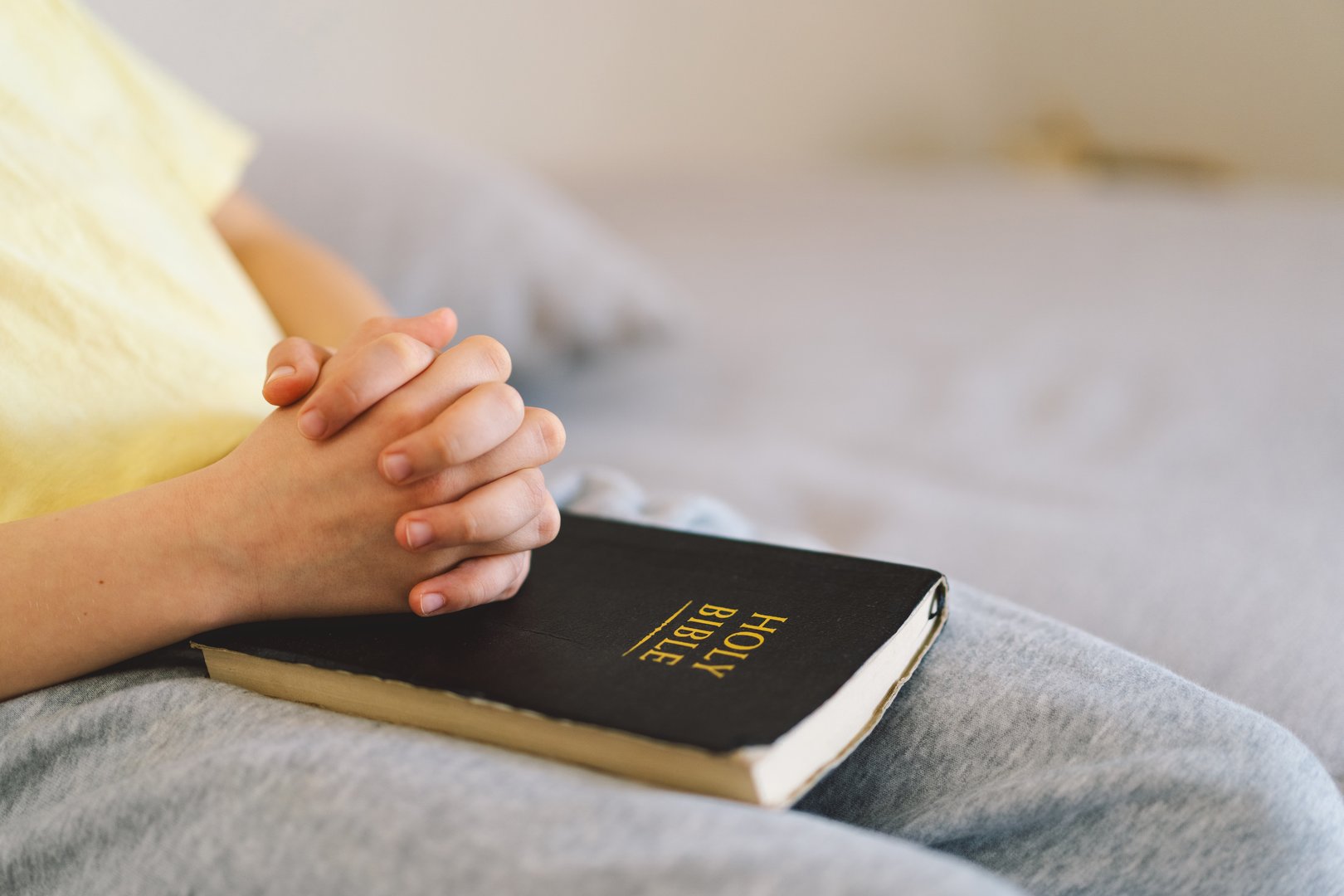 A boy is reading the holy bible and praying or meditating. Concept of Christianity, religion and faith.