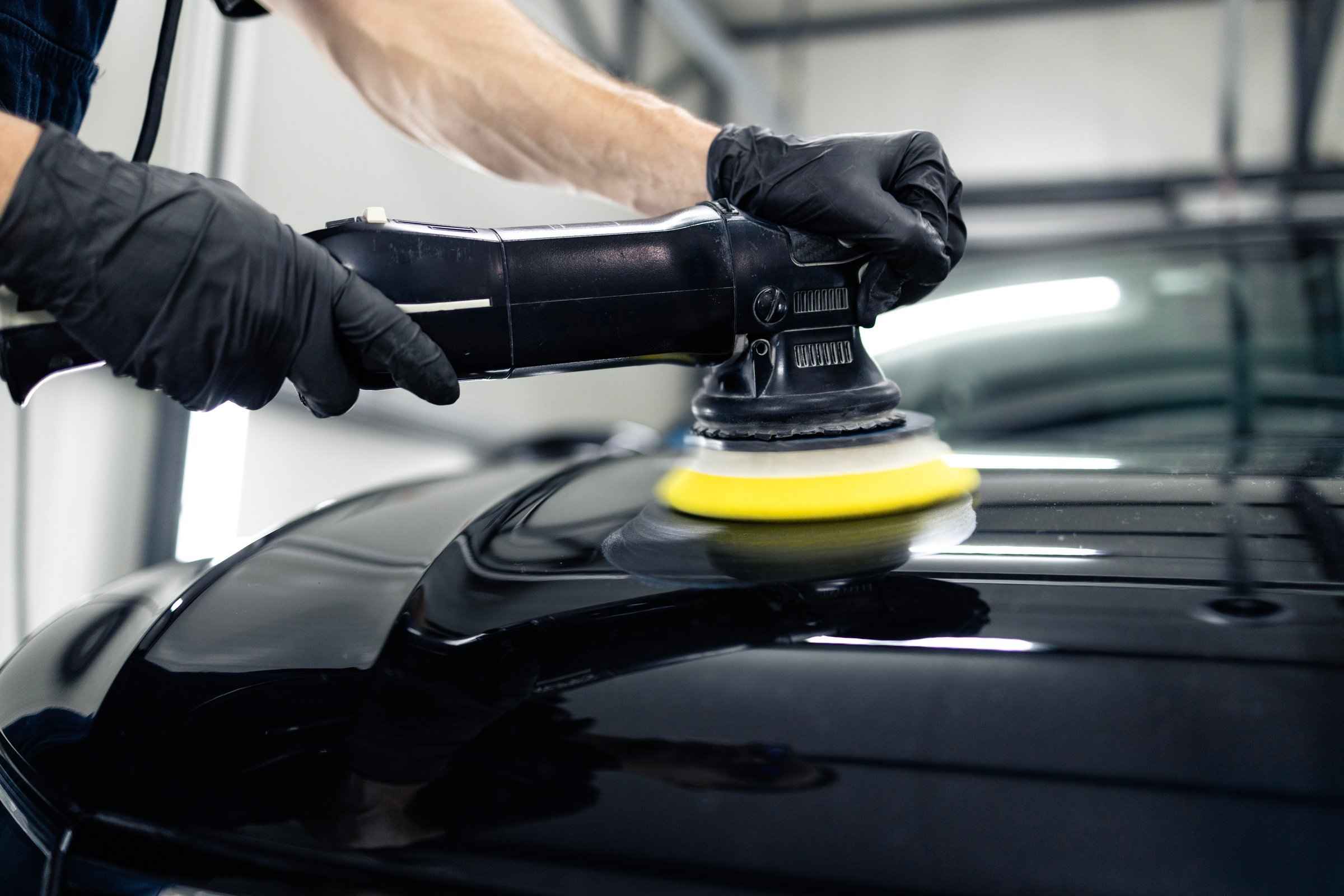 Close up view of vehicle polisher tool rotating and polishing car hood.