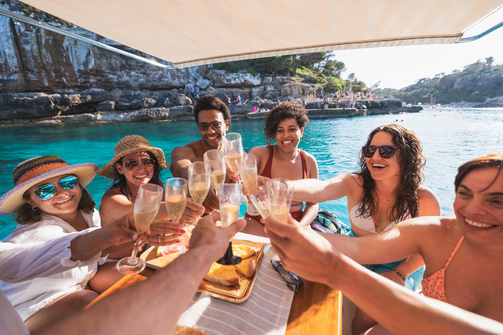Happy tourists sharing drinks and smiles during a boat trip at sea. Summer, vacation, boat concept