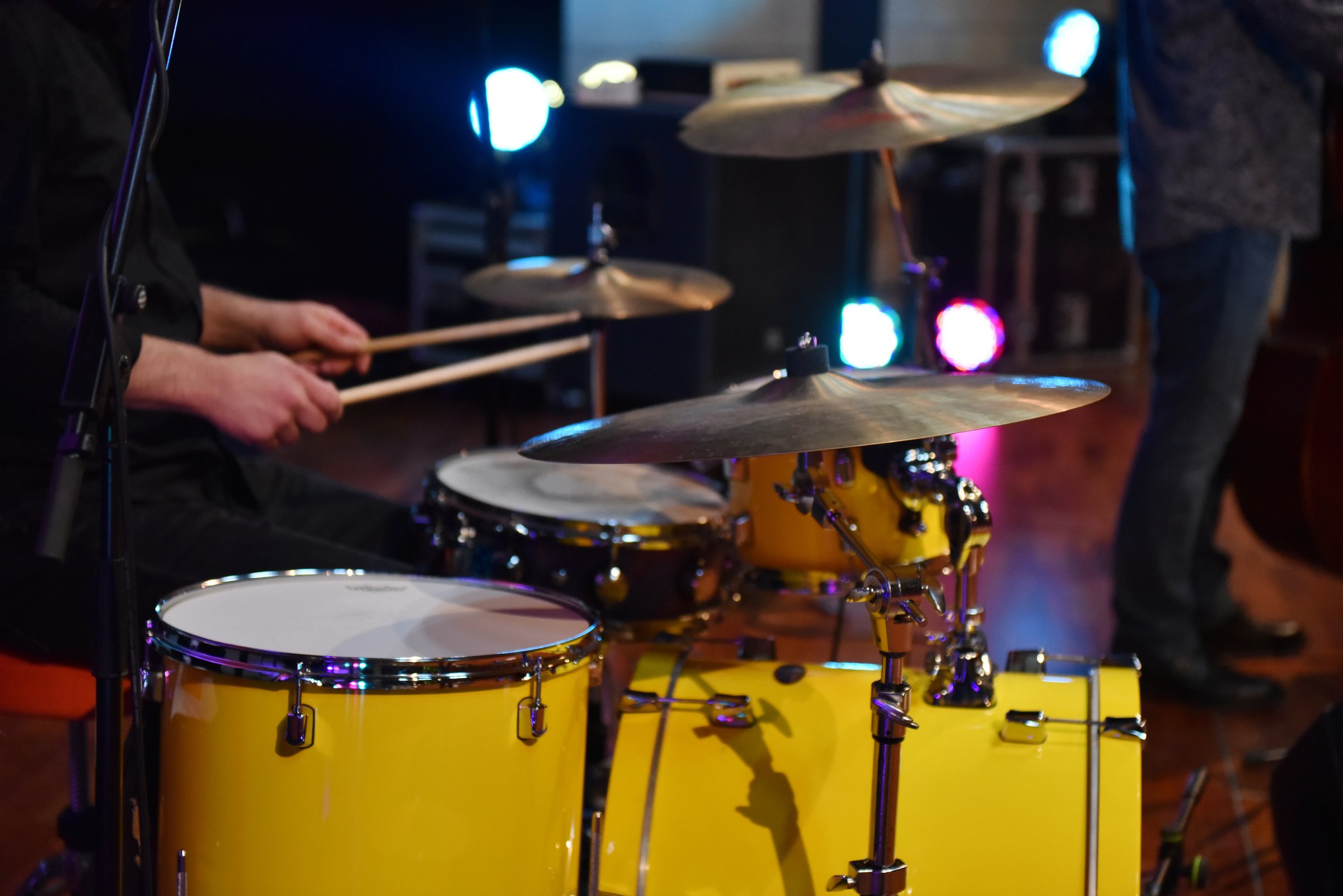 Drummer playing on stage on yellow drum kit at blues concert