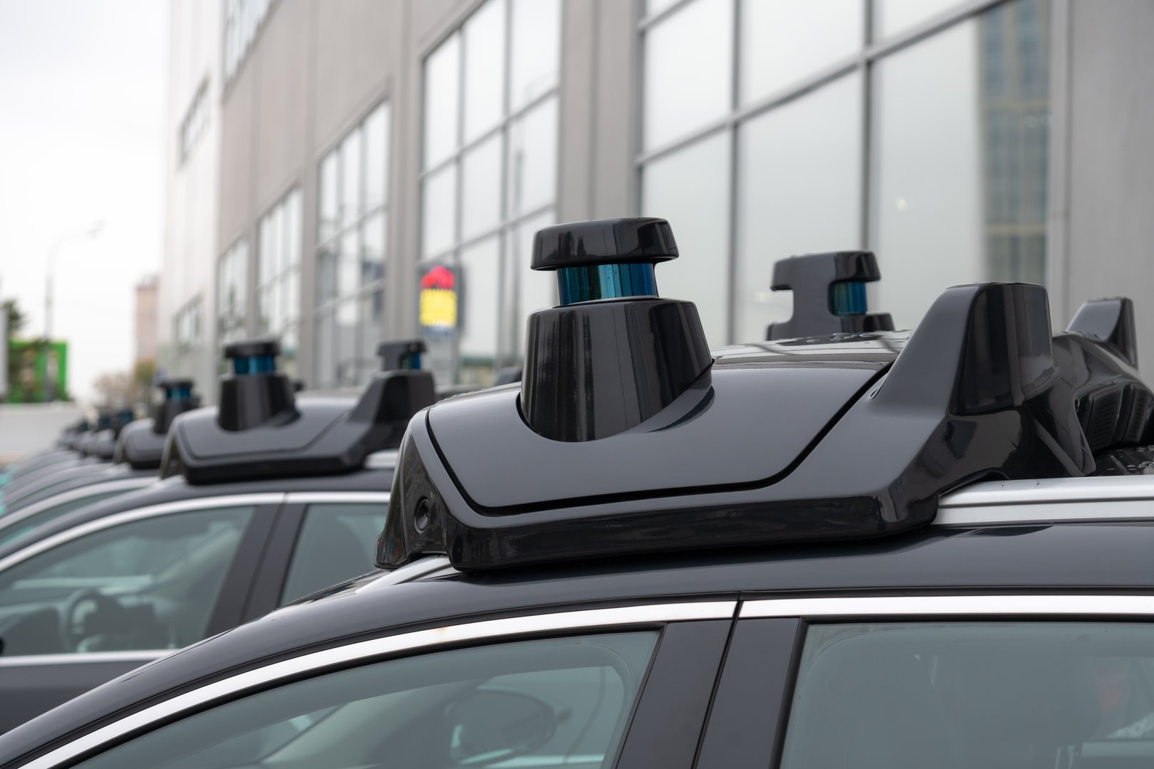 Close-up view of sensors and radar on roof of black autonomous driving vehicle (self-driving car or driverless car). Soft focus. Copy space. Futuristic transportation technology theme.
