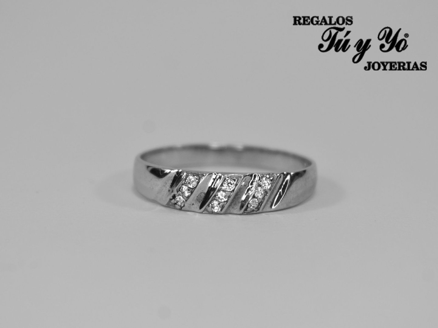 Silver ring with diagonal grooves and embedded stones, displayed against a plain background. Bold text in the corner.