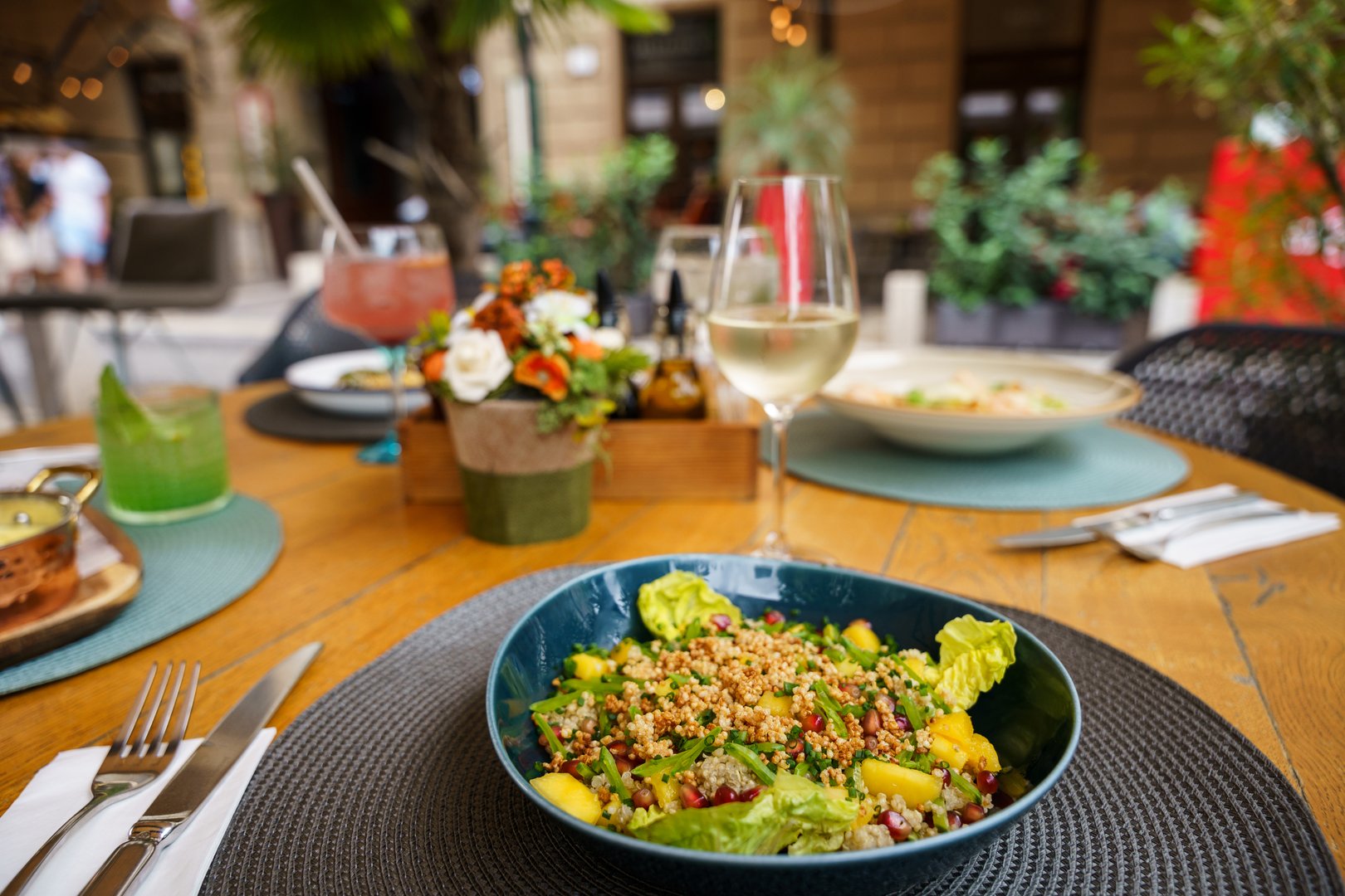 A vibrant quinoa and mango salad served in a deep blue bowl, garnished with fresh lettuce and sprinkled with herbs and seeds.