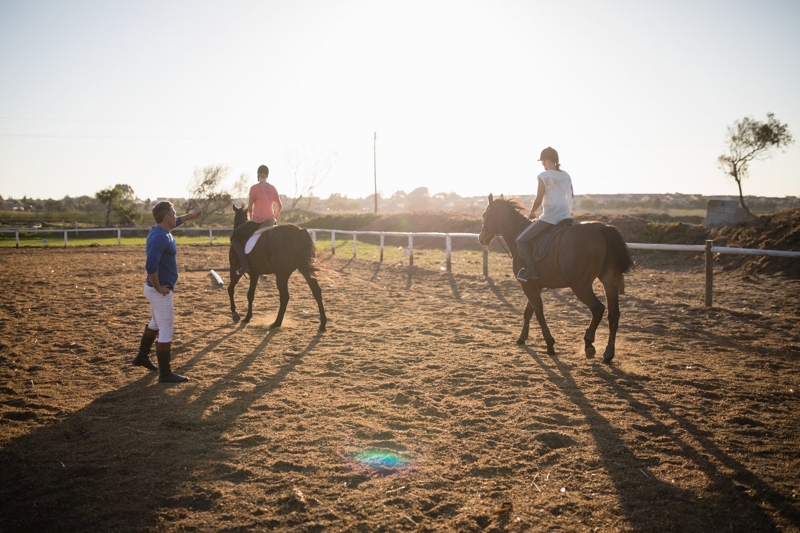 Trainer guiding young women in riding horse at barn