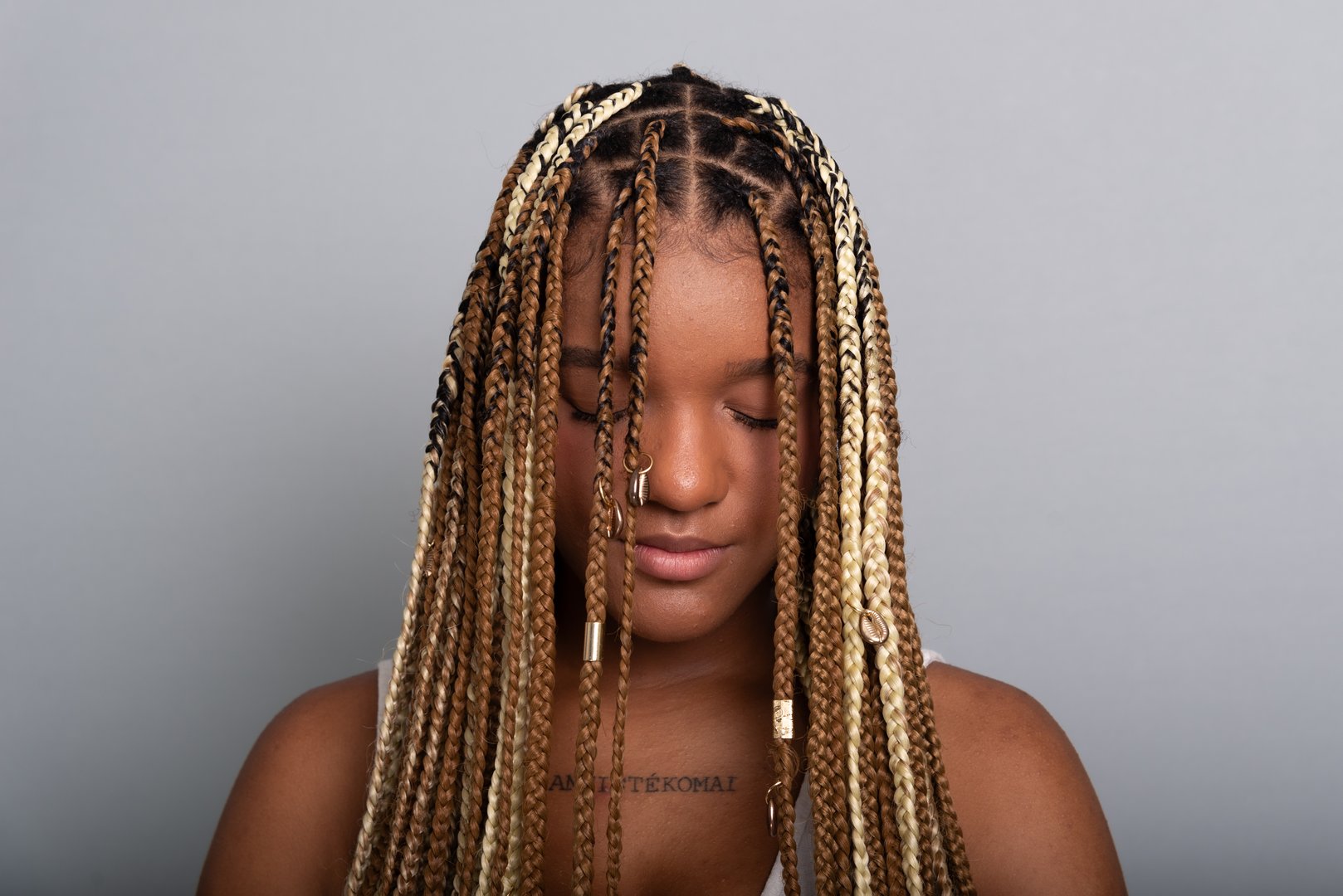 Close-up portrait of beautiful brunette woman with braids in her hair, calm and confident. Isolated on gray studio background.