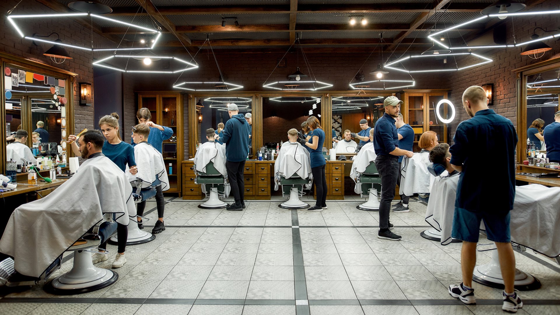 People at barbershop. Professional barbers serving clients in the modern loft style barber shop. General view. Hairdresser services. Hair cutting, hairdressing, shaving, grooming