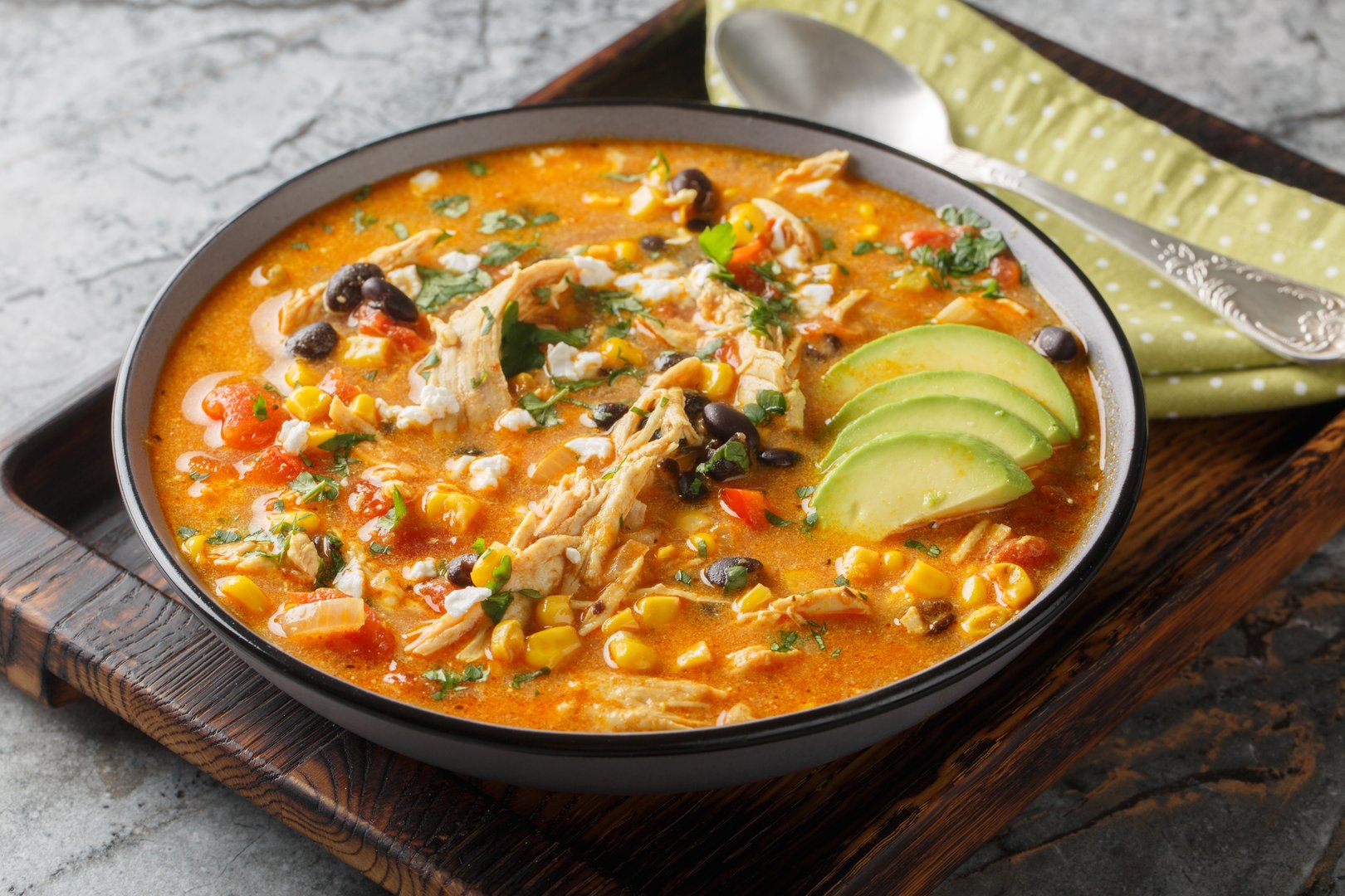 Creamy Mexican chicken enchilada black bean soup closeup on the plate on the table. Horizontal