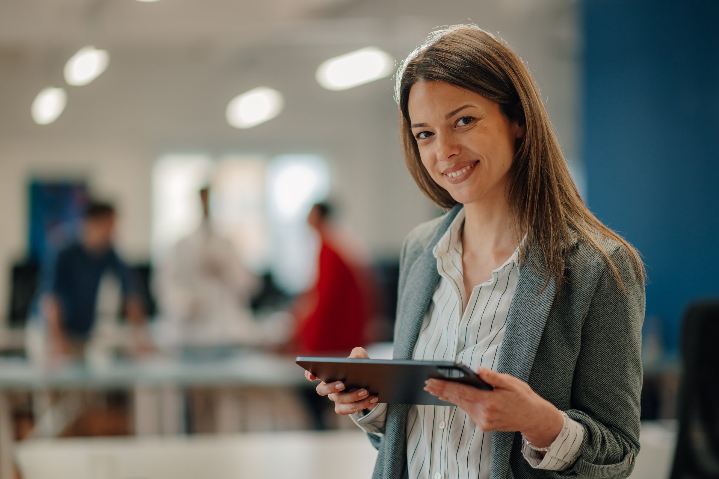 Portrait of a businesswoman holding digital tablet and smiling at the camera in a modern office