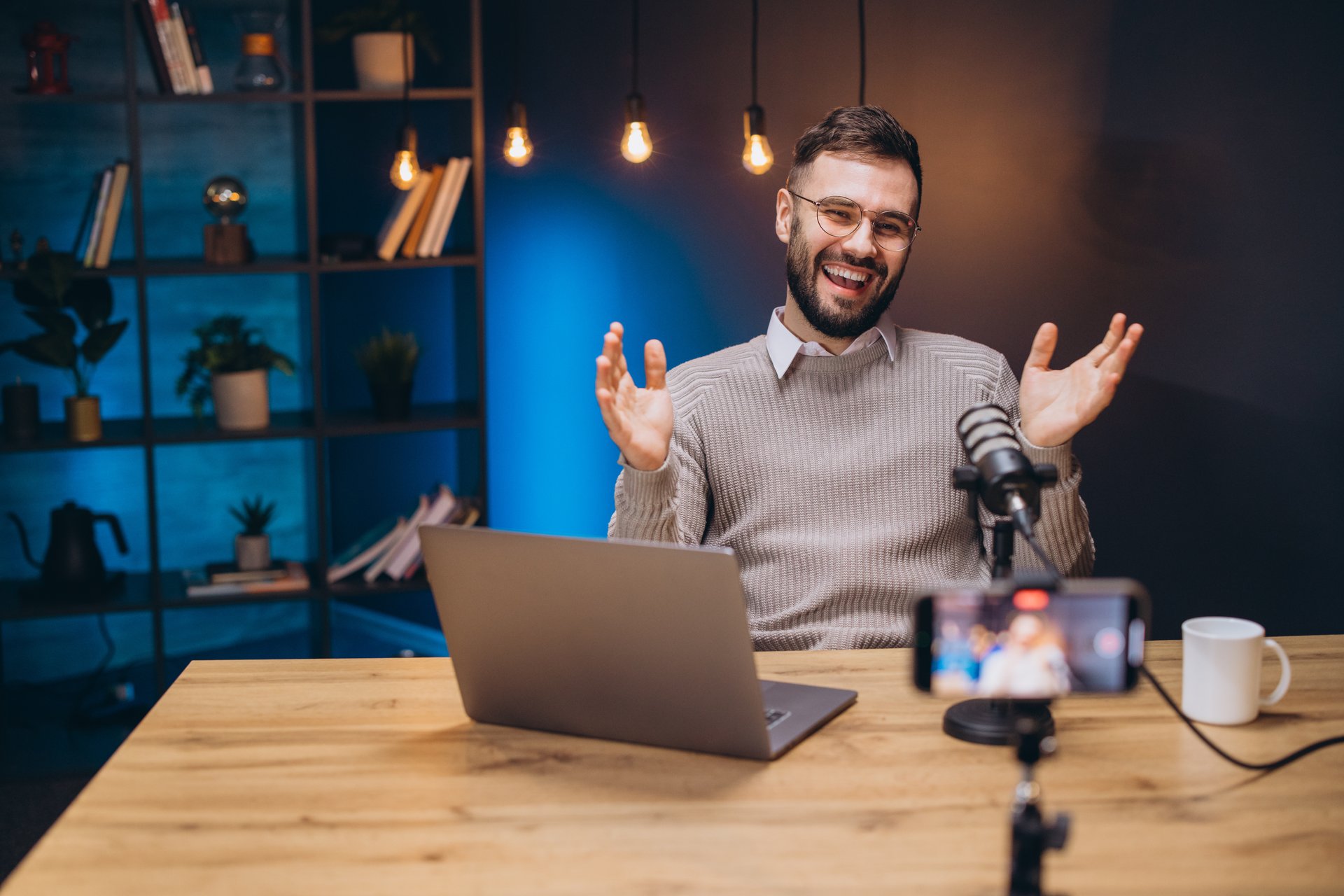 Professional male podcaster talking animatedly while recording audio podcast in home studio, wearing headphones near microphone