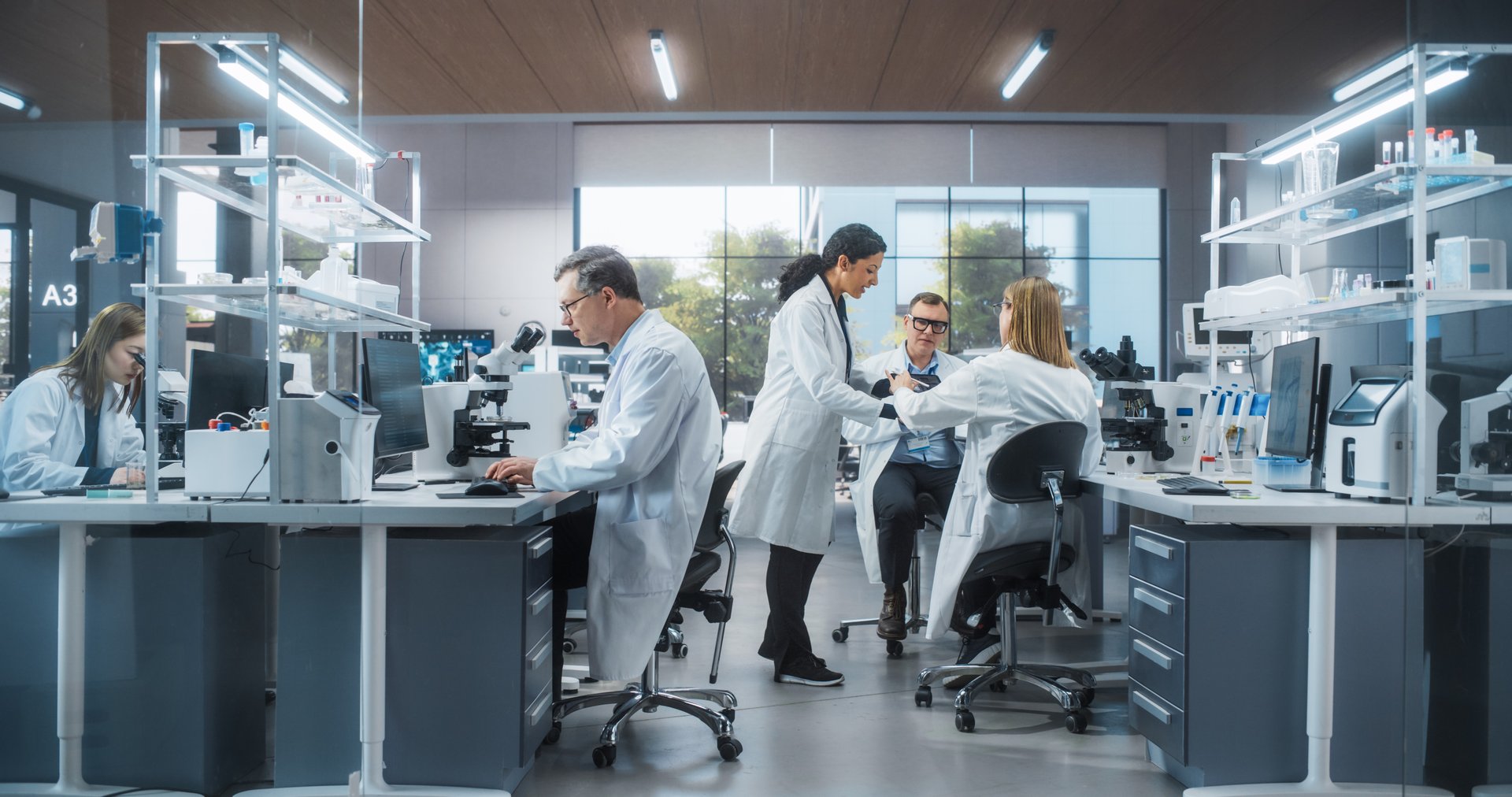 Three Scientists Discussing Latest Bioengineering Discoveries and Sharing Research Data on Vaccine Efficacy. Diverse Male and Female Colleagues Working in a Modern Medical Research Center