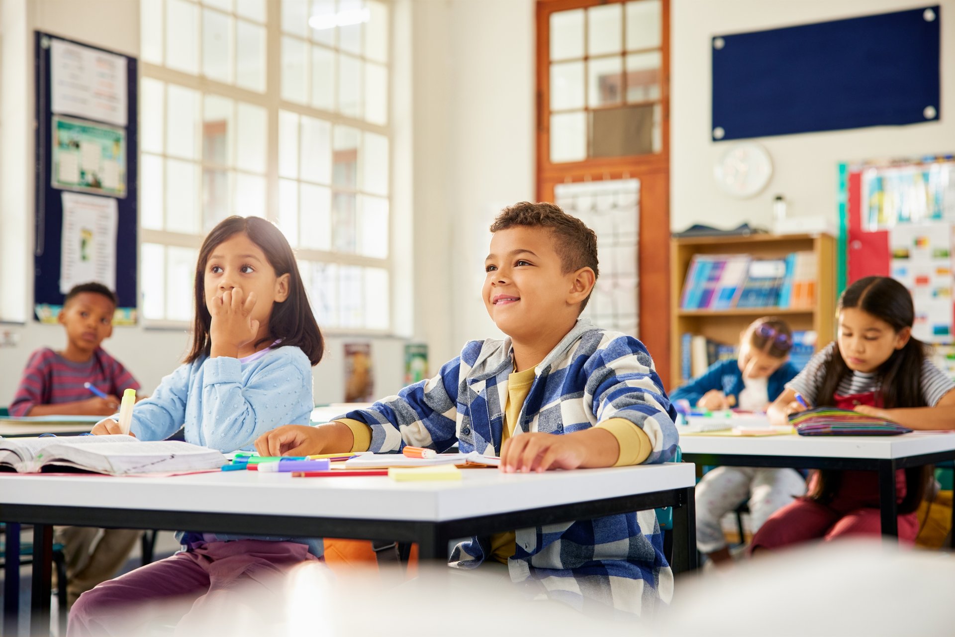 Happy primary school children learning in classroom