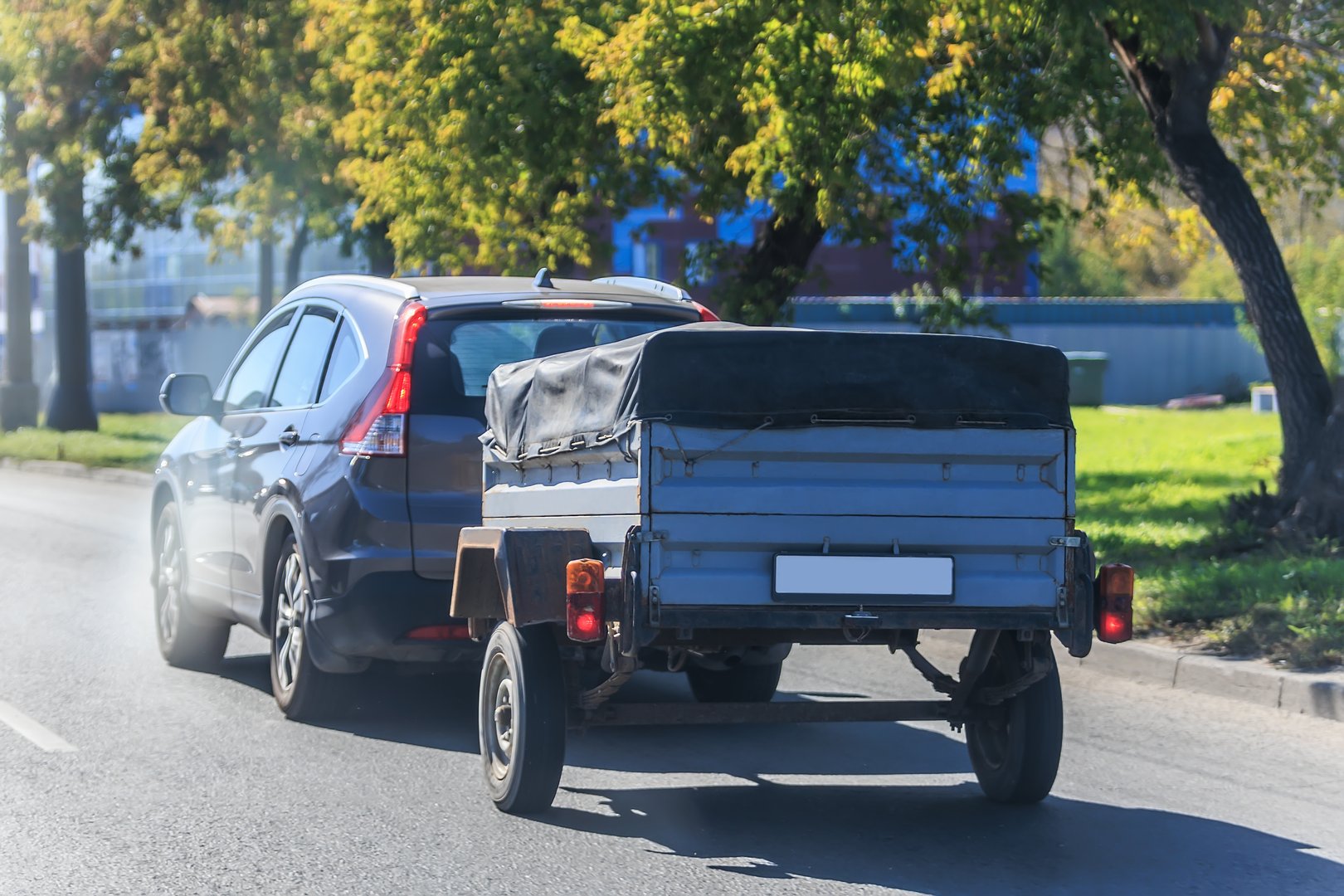 SUV with trailer moving along city street close-up