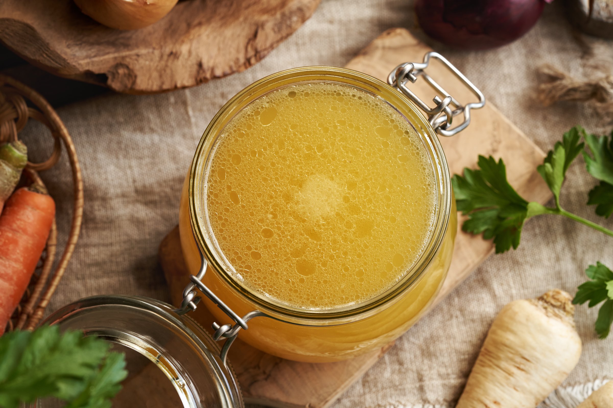 Chicken soup or bone broth in a glass jar with carrots, parsley and onions