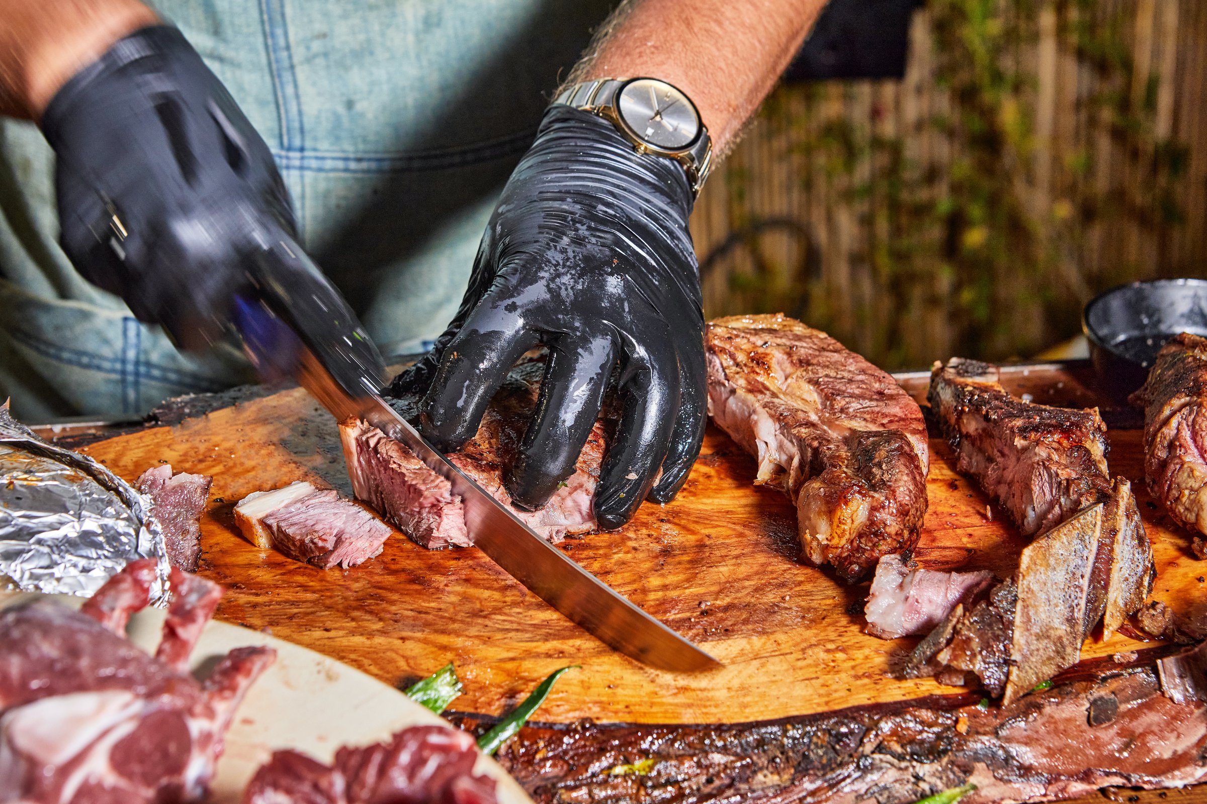 Persona manipulando carne cruda con guantes de nitrilo en ambiente higiénico.
