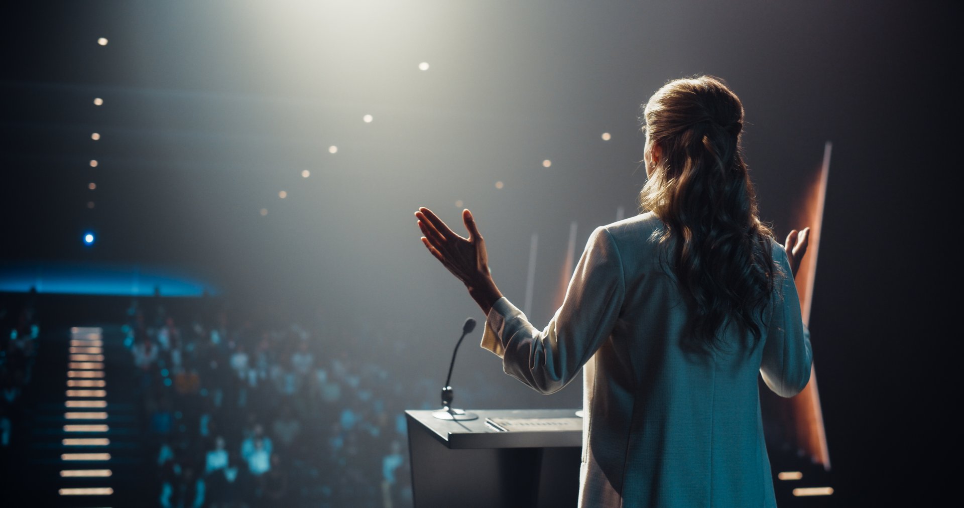 Caucasian Female Speaker with Expertise in Technology, Finance, Business, Politics, and Religion Coaching a Diverse Group of Young Specialists During a Presentation at a Strategic Growth Conference