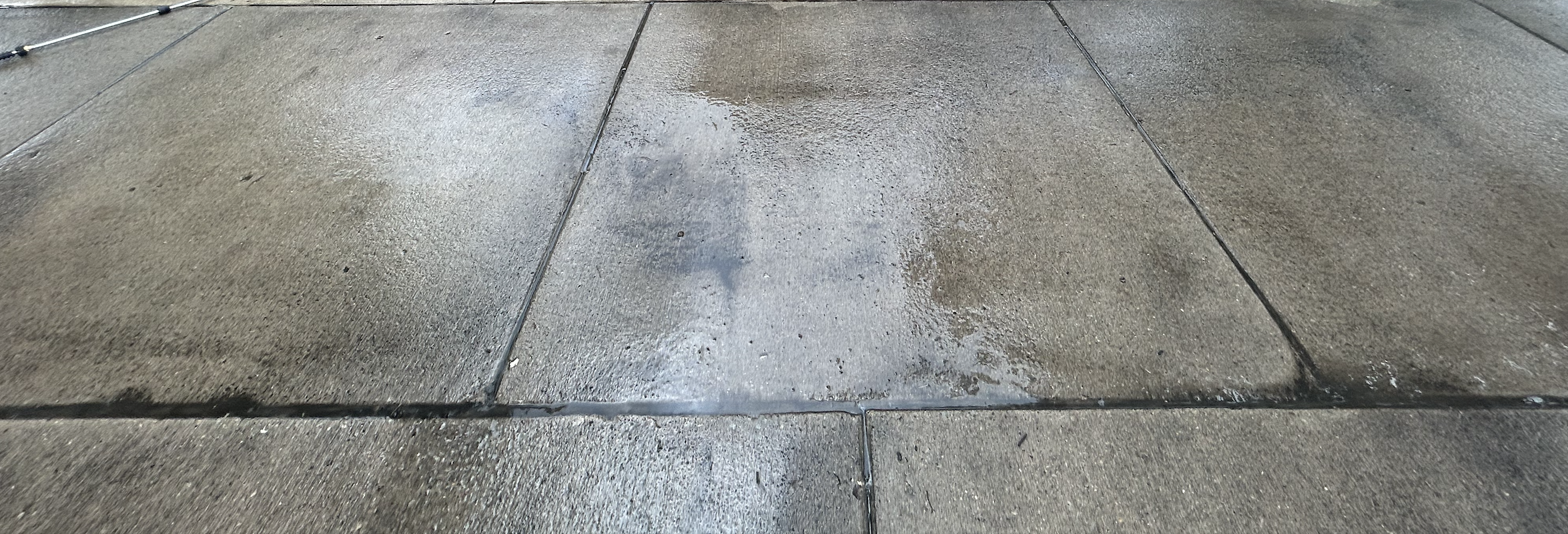 Driveway before pressure washing showing dirt and stains