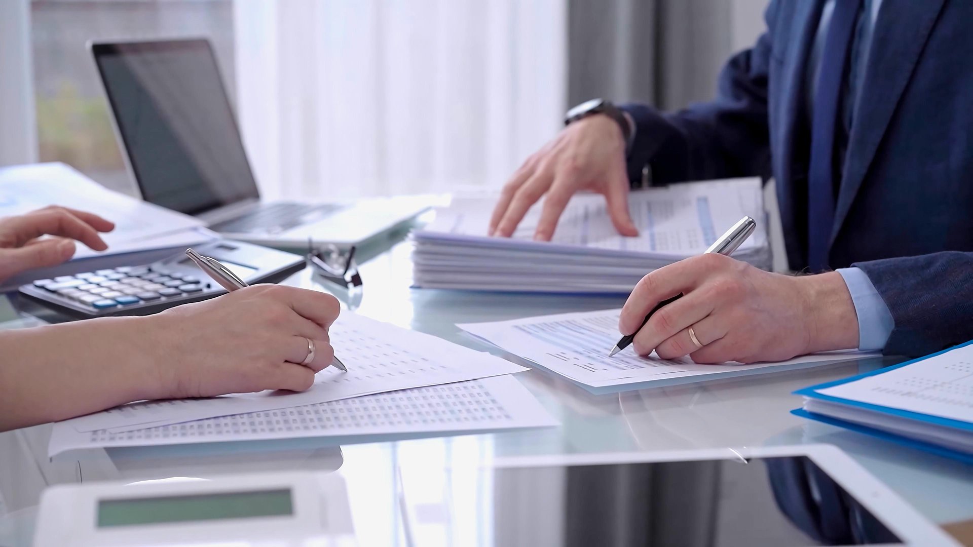 Business colleagues accountants or auditors reviewing financial data in office. Two professionals analyzing paper reports and using calculators. Audit and taxes.