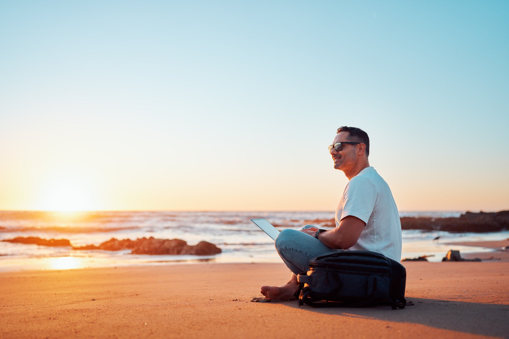 Freelancer enjoying working on the beach at sunset